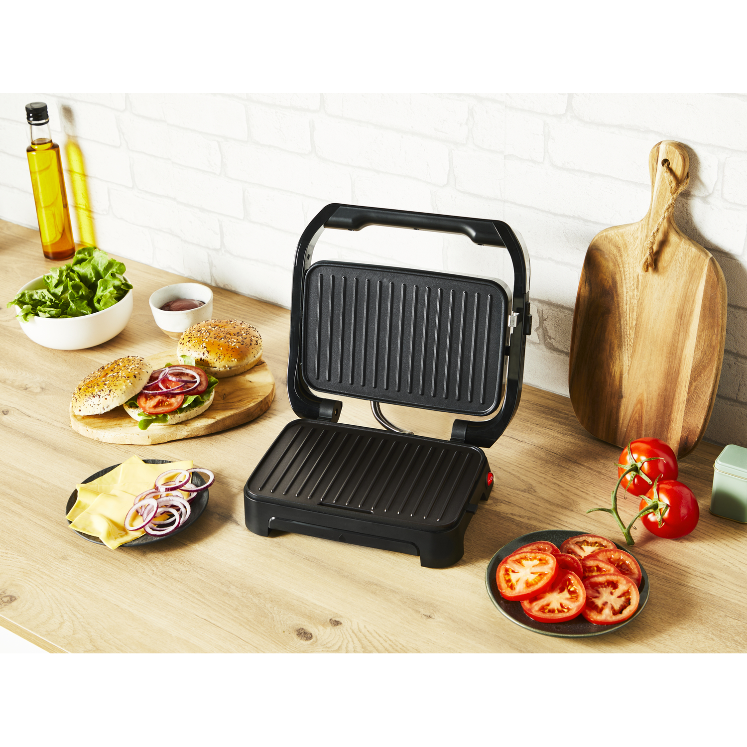 Een zwarte grill met eten aan de zijkant. Hamburgers, kaas, tomaten en kruiden.