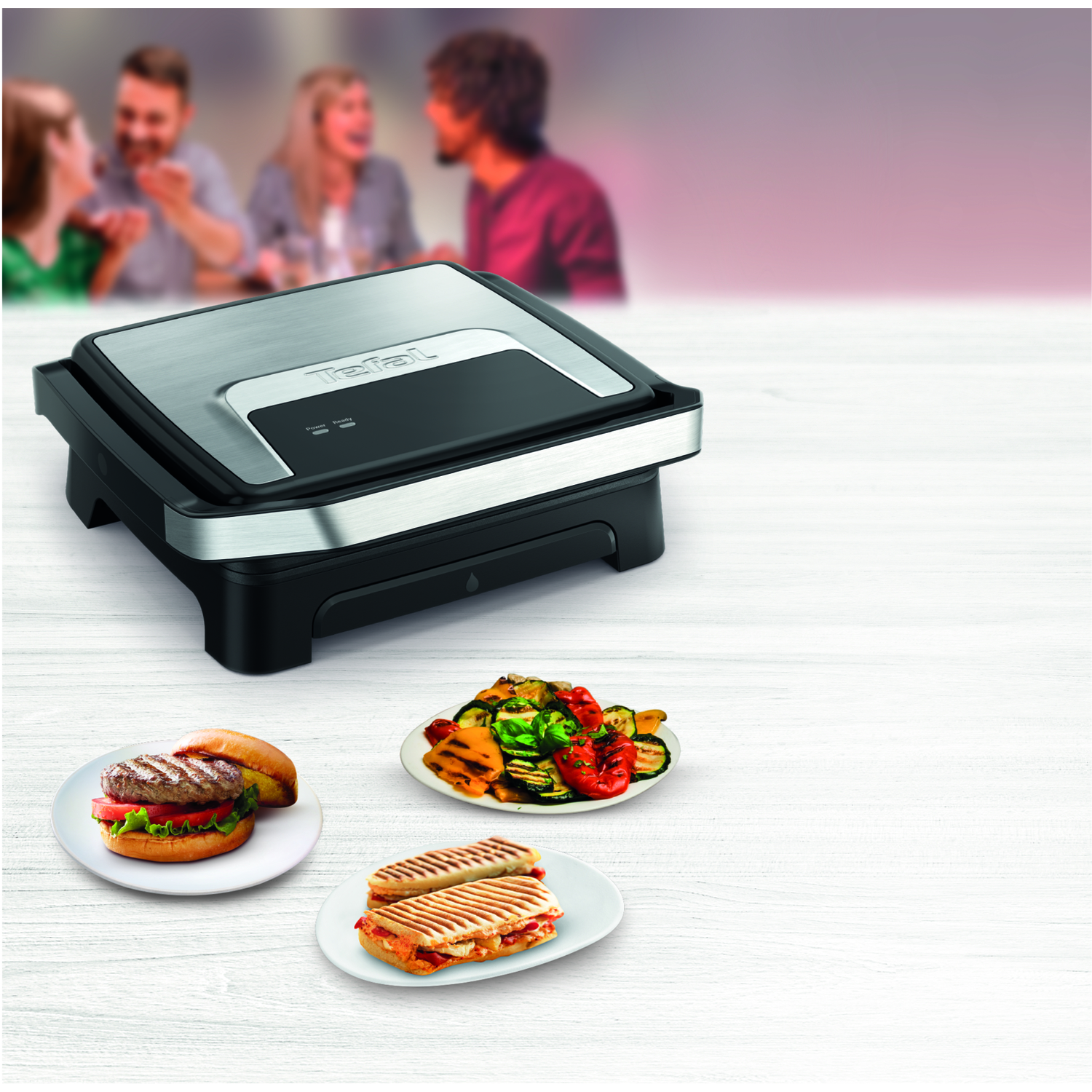 Grill with food, including a burger and sandwiches. People are blurred in the background.