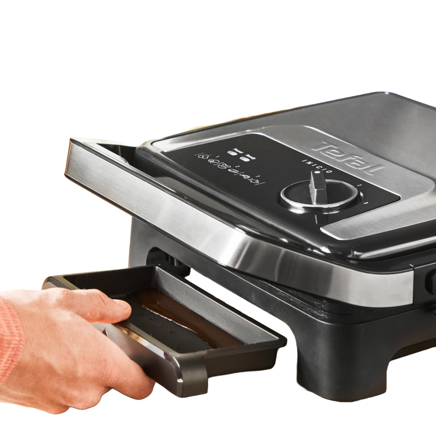 A Tefal grill with an open lid. A hand removes the drip tray.