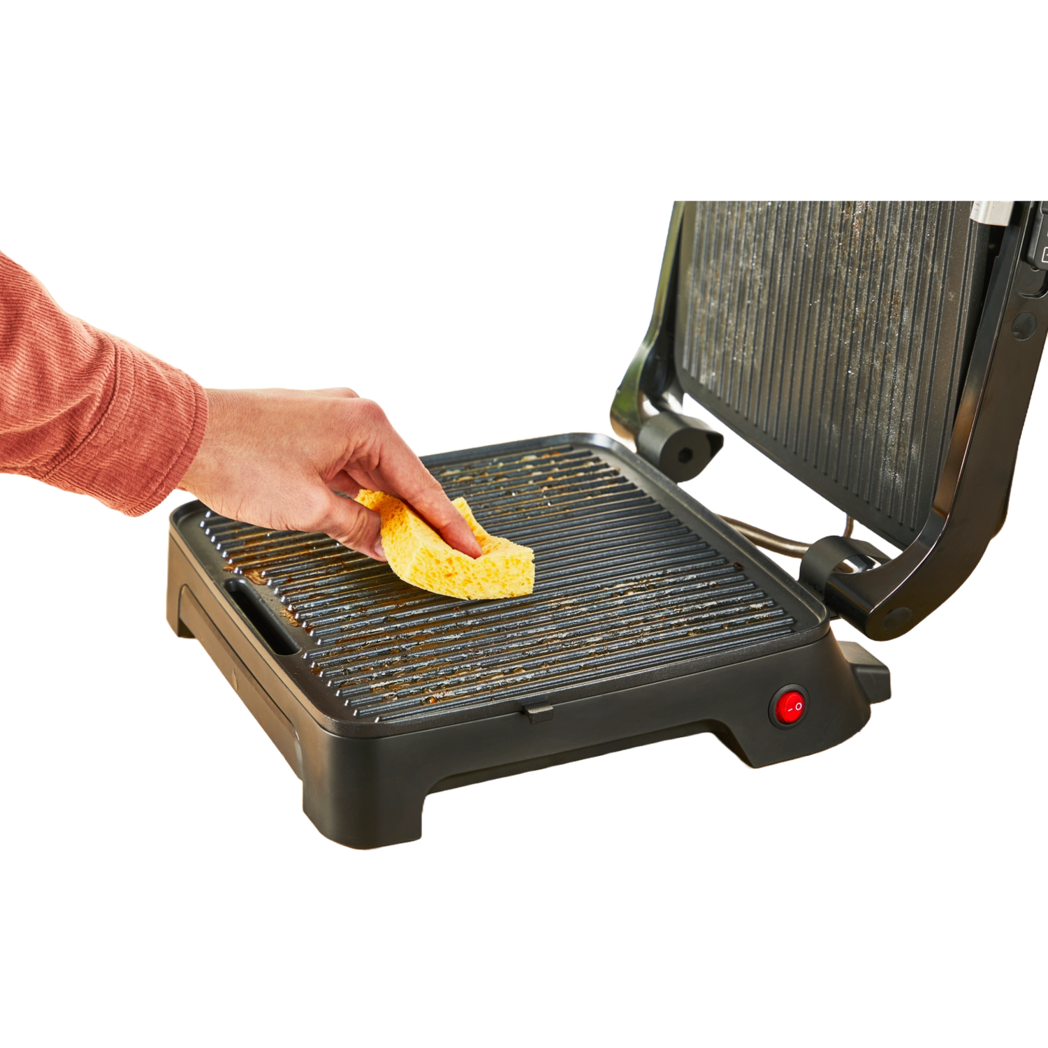 A person cleaning a grill with a yellow sponge, isolated on black.