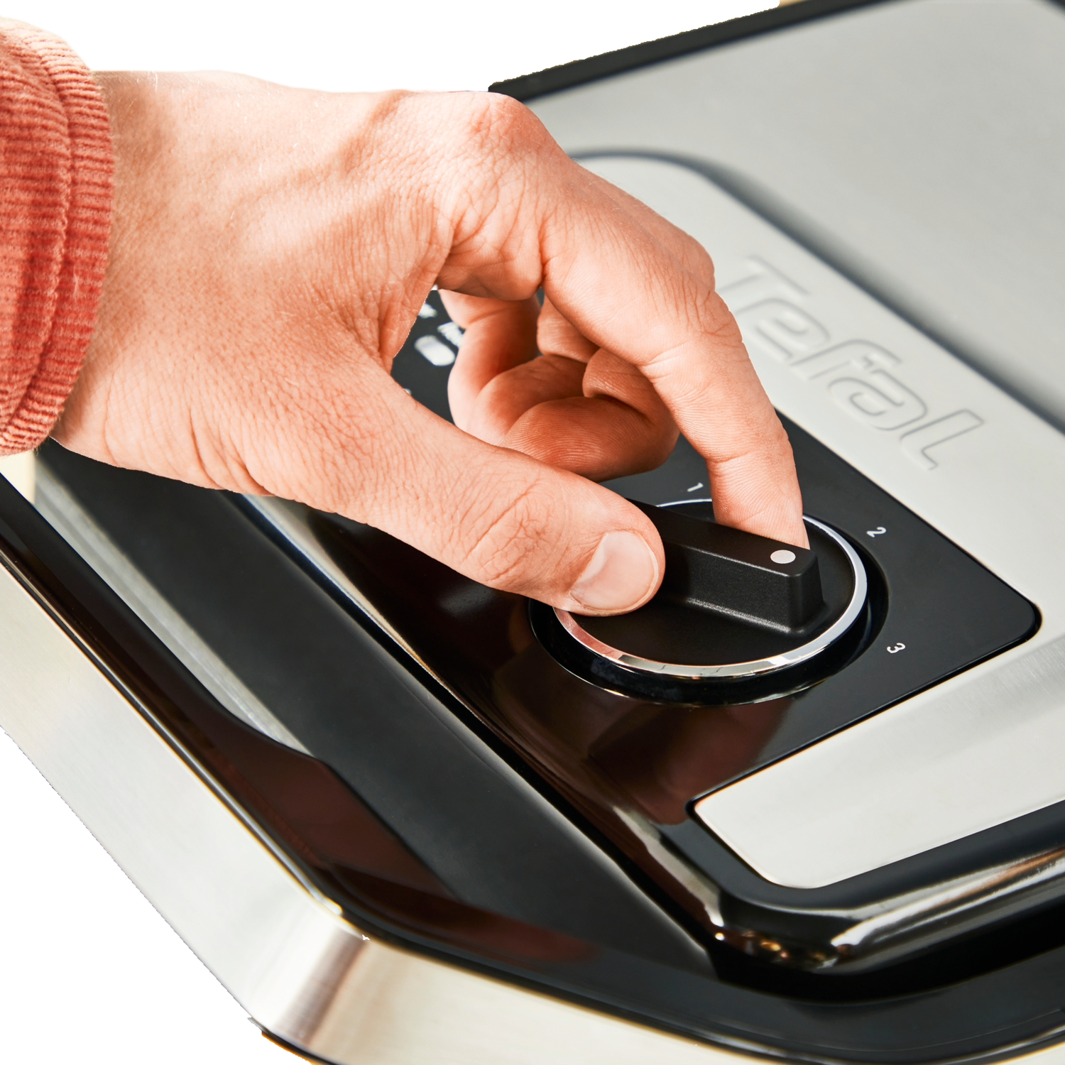 Hand adjusting the temperature dial on a Tefal grill.
