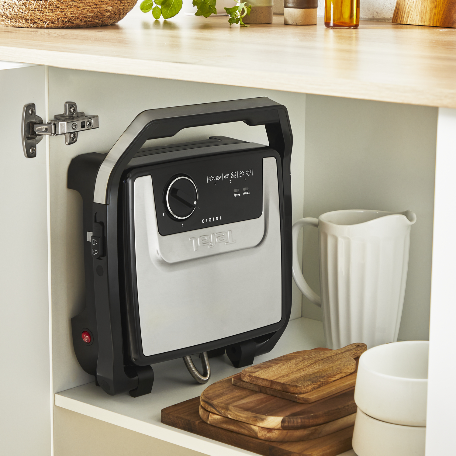 Kitchen appliance in cupboard. Black and silver appliance, wooden shelves.