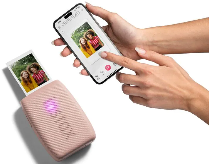 Un téléphone affiche une photo de deux femmes. Une imprimante à côté imprime la même photo. Des mains tiennent le téléphone et l'imprimante.