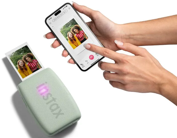 Main tenant téléphone avec photo, imprimante avec photo imprimée. Les deux montrent femmes souriantes.