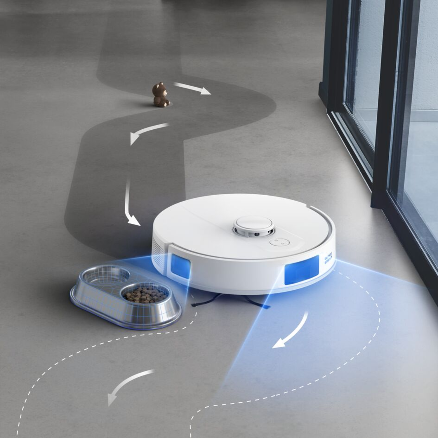 A white robot vacuum cleaner cleaning a gray floor. A pet bowl and a small toy are visible.
