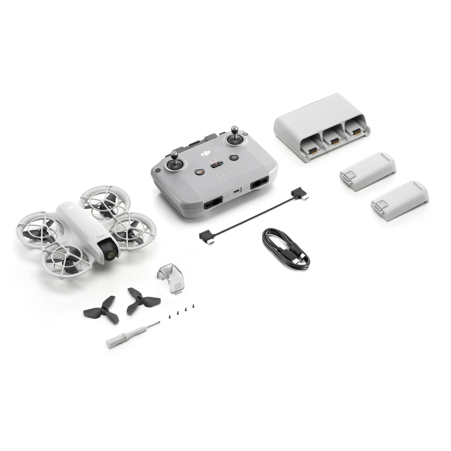 Kit de drone avec drone, télécommande, hélices supplémentaires, chargeur, câbles et accessoires. Fond blanc.