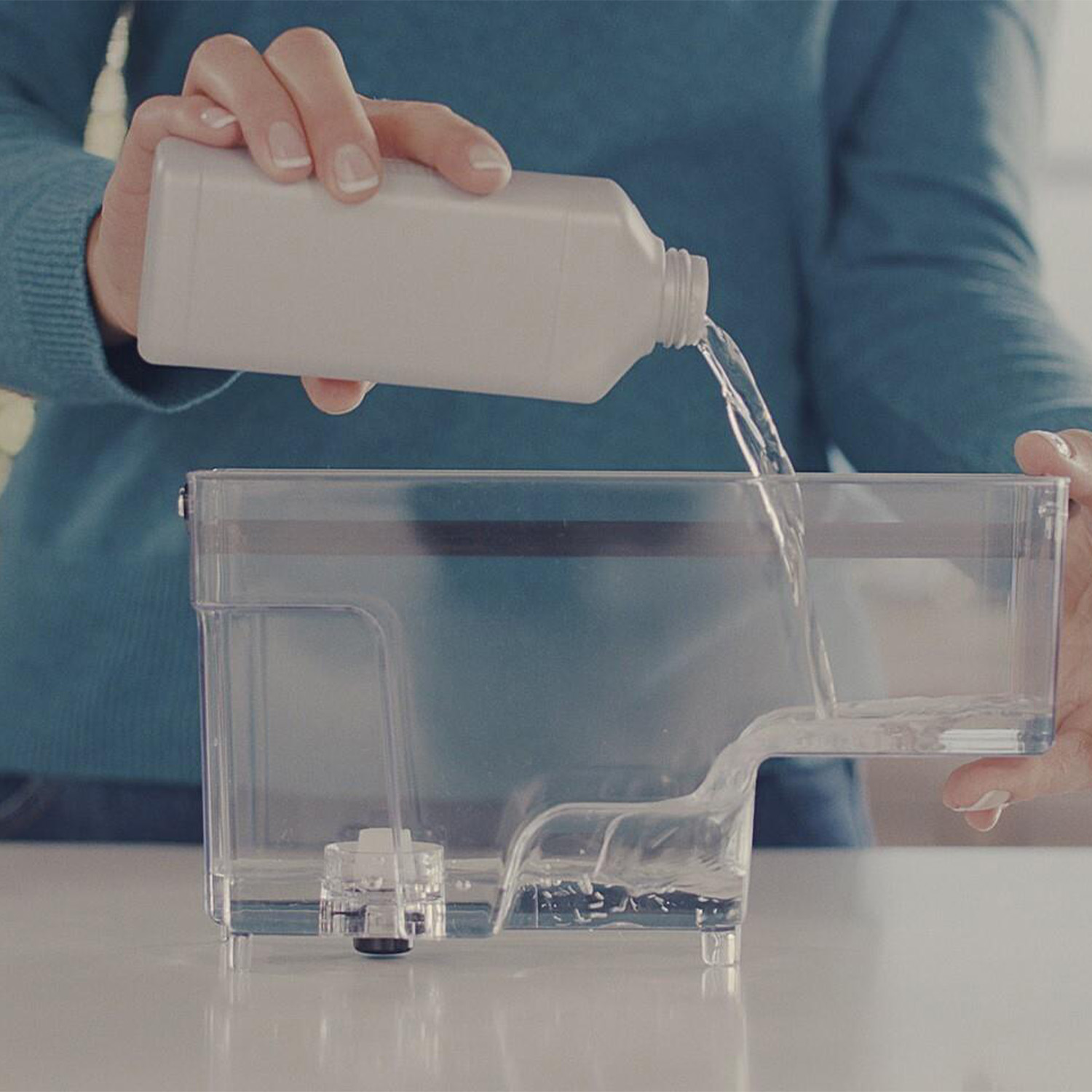 Una persona versa del liquido da una bottiglia in un contenitore trasparente.