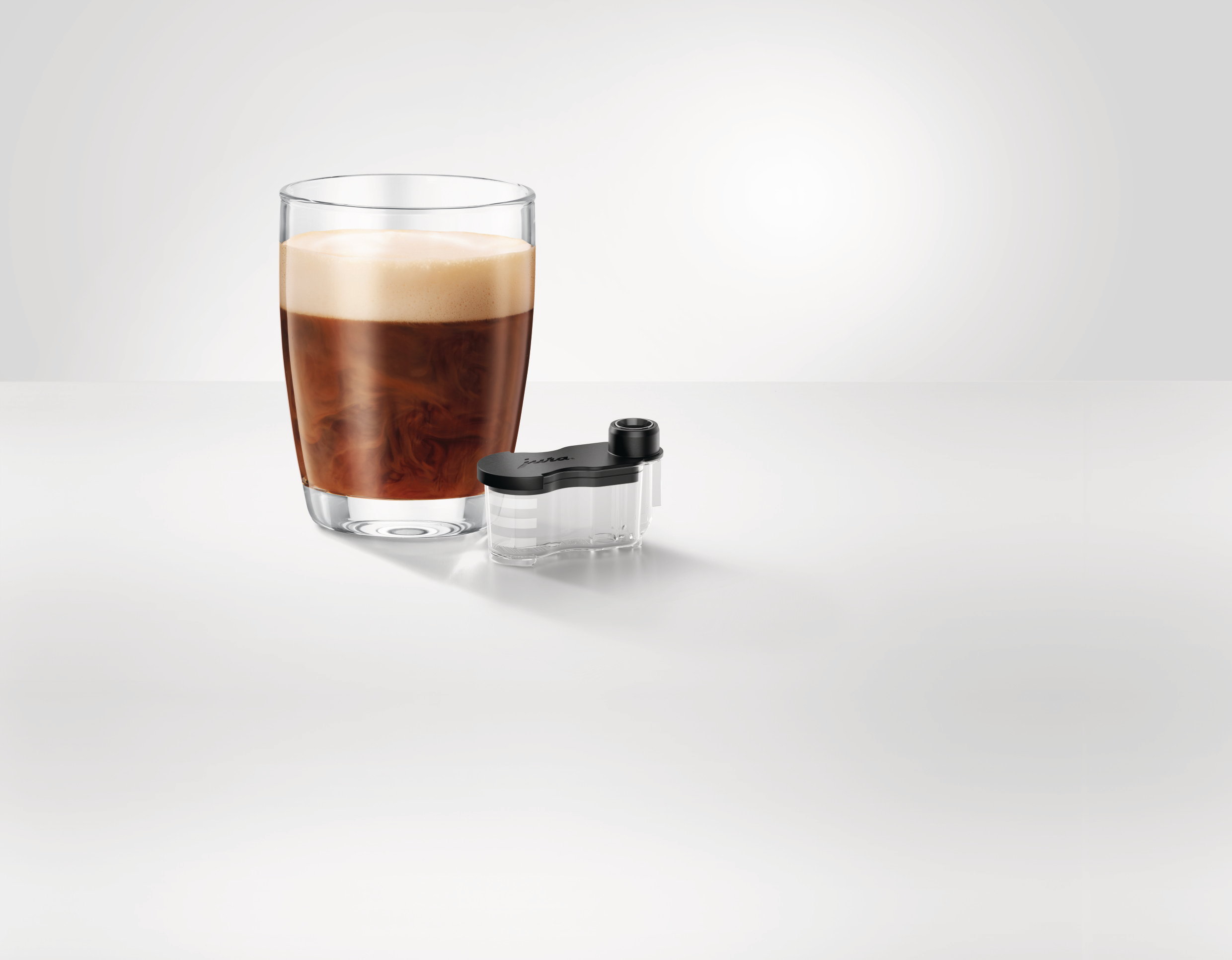 Glas Kaffee, weißer Tisch, Kaffeemaschinenteil.