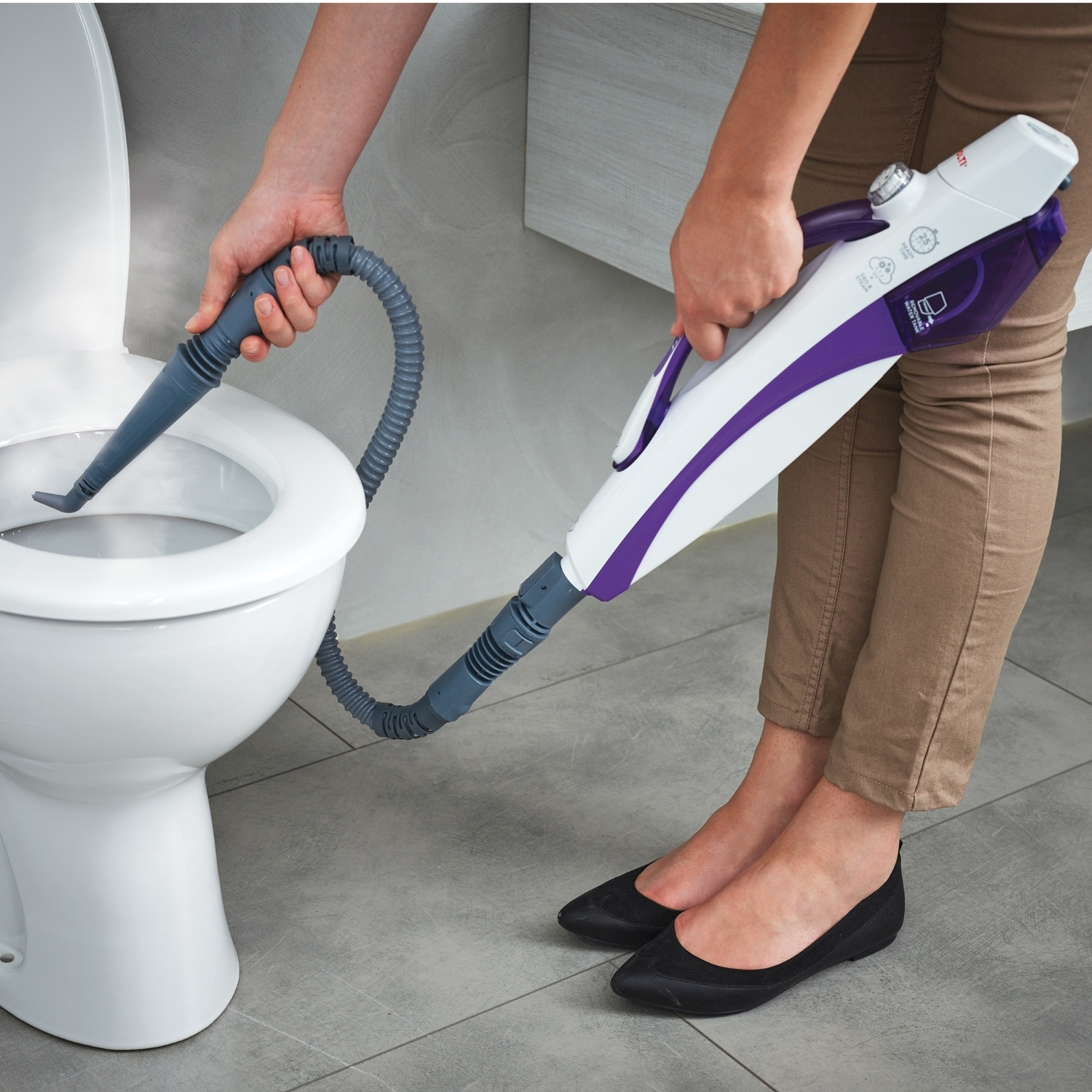 Una persona pulisce un water con un pulitore a vapore portatile.
