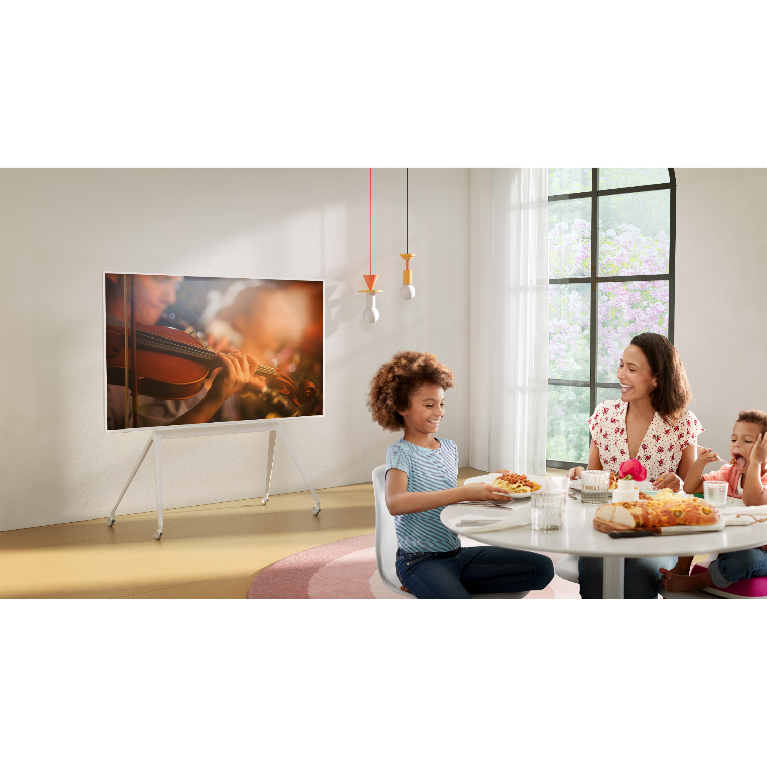 Family eating around a white table with a TV in the background.