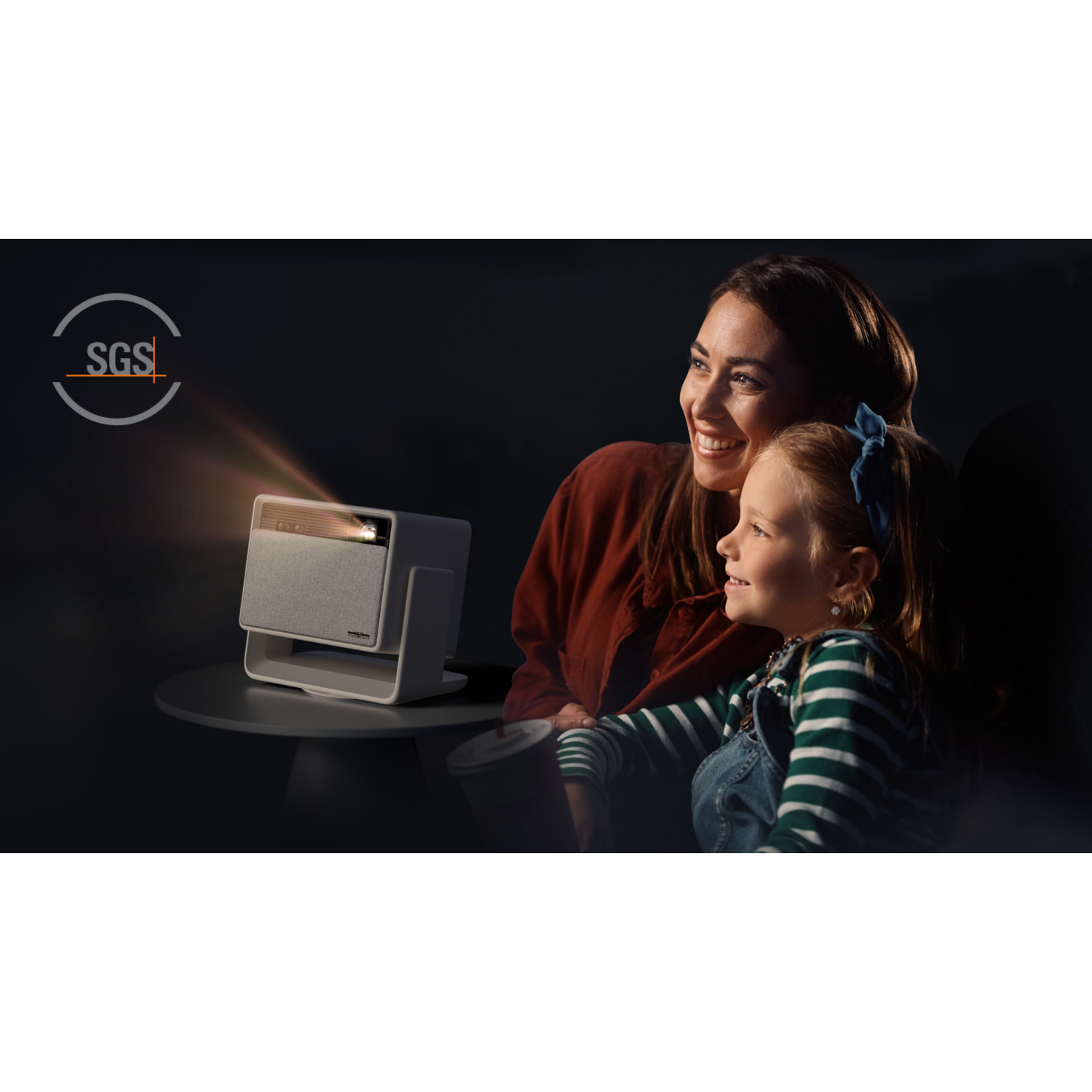 A woman and a child watch a projector's image. The projector sits on a table.