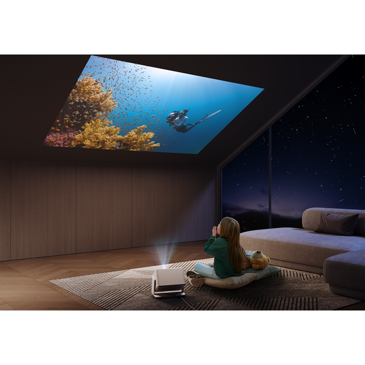 A girl watches a projection of divers in the sea on a ceiling. A sofa is to the right. Night view.