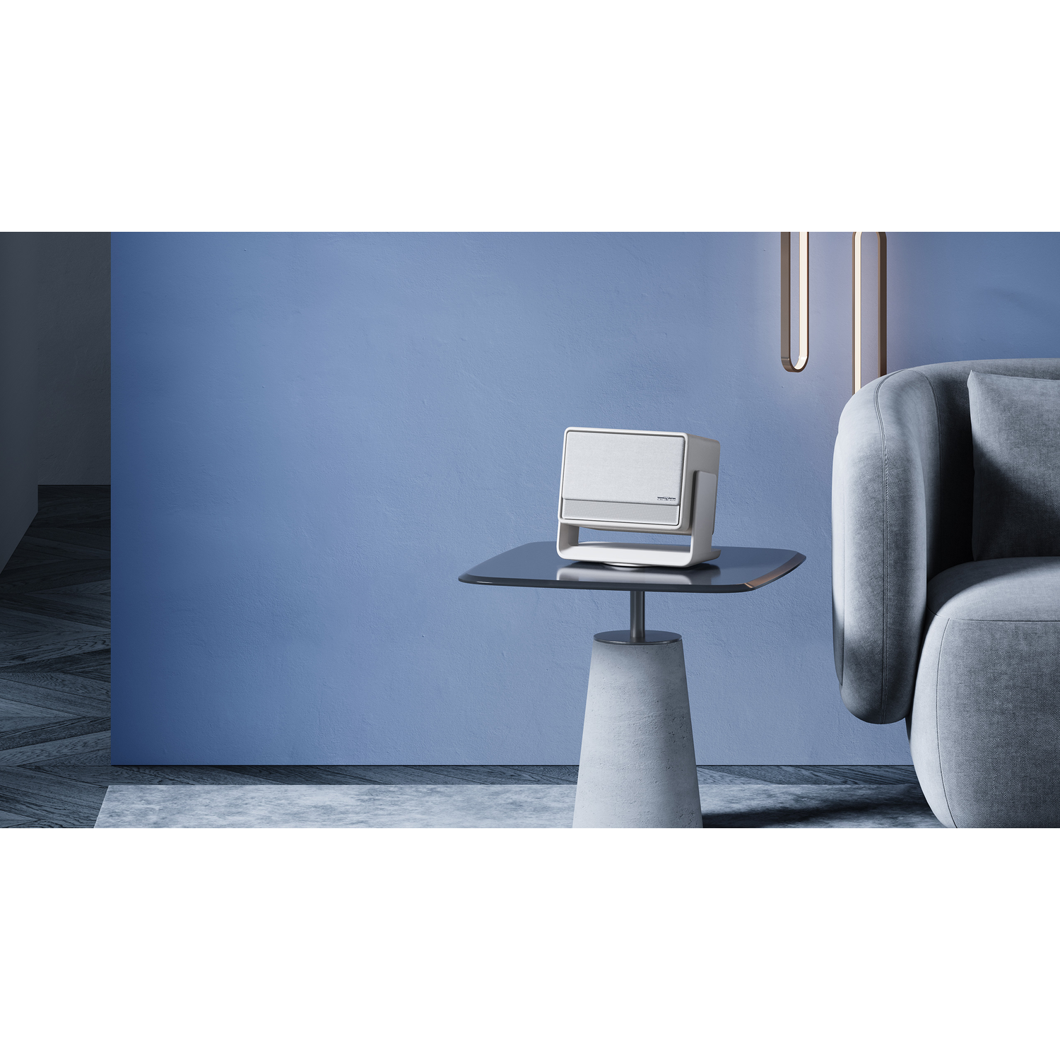 A modern white and silver speaker on a glass table, set against a blue wall and sofa.