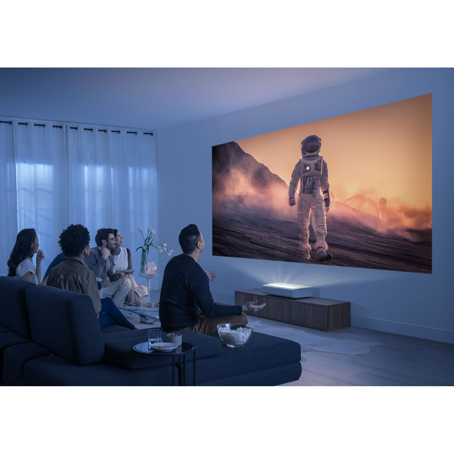 Mensen kijken naar een geprojecteerd beeld van een astronaut. Een witte projector staat ervoor.
