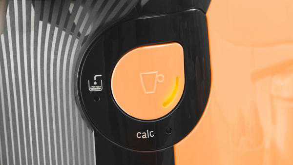 Nahaufnahme einer schwarz-orangenen Kaffeemaschine mit beleuchteter Taste.
