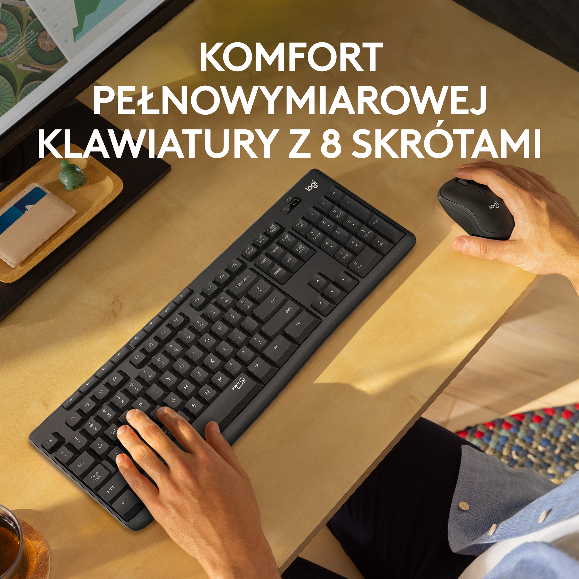 Pełnowymiarowa czarna klawiatura i mysz leżą na jasnym drewnianym biurku.