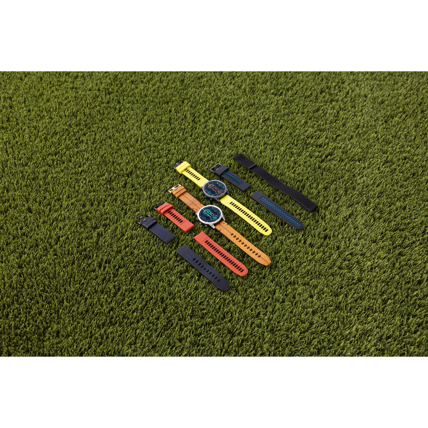 Montres et bracelets exposés sur de l'herbe verte. Différentes couleurs, vue de dessus.