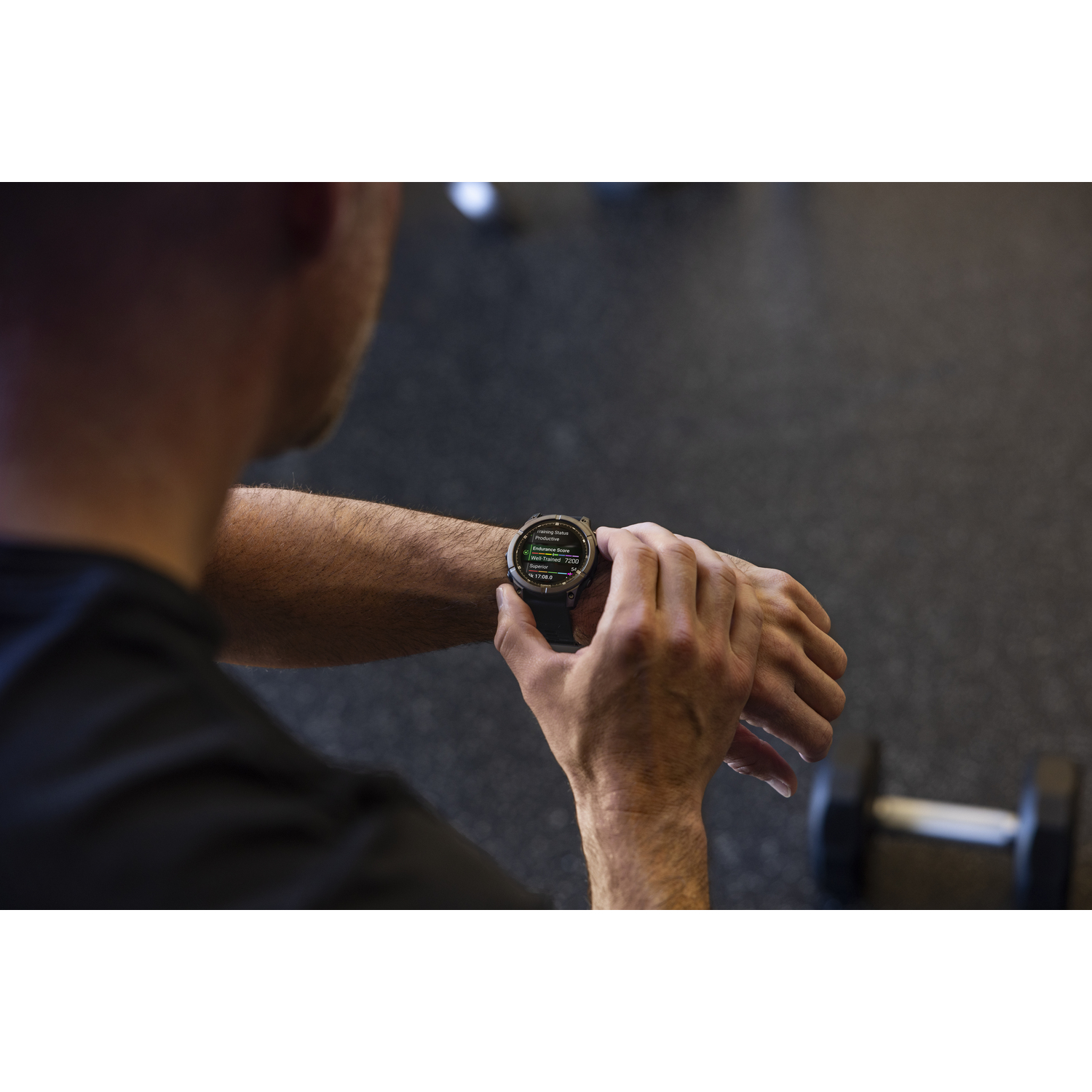 Man die in de sportschool naar een smartwatch kijkt.