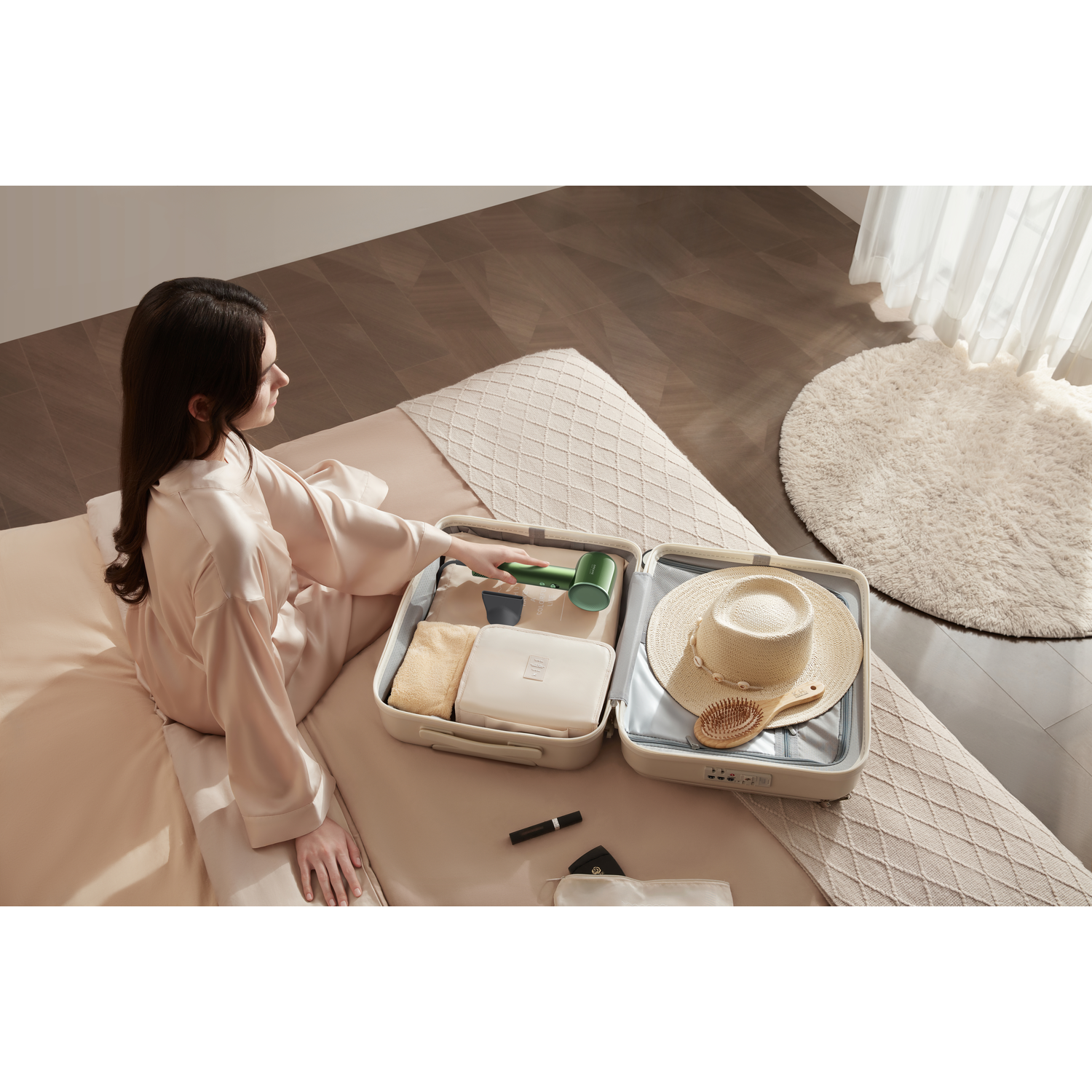 A woman packing a suitcase with clothes, accessories, and a hat.