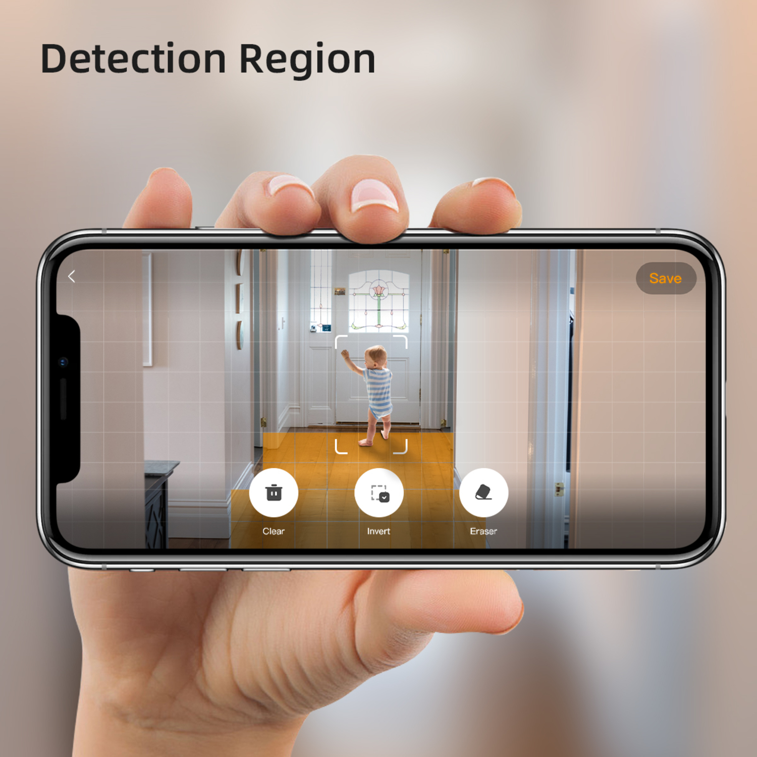 A hand holding a phone displaying a baby in a doorway with a detection region overlay.