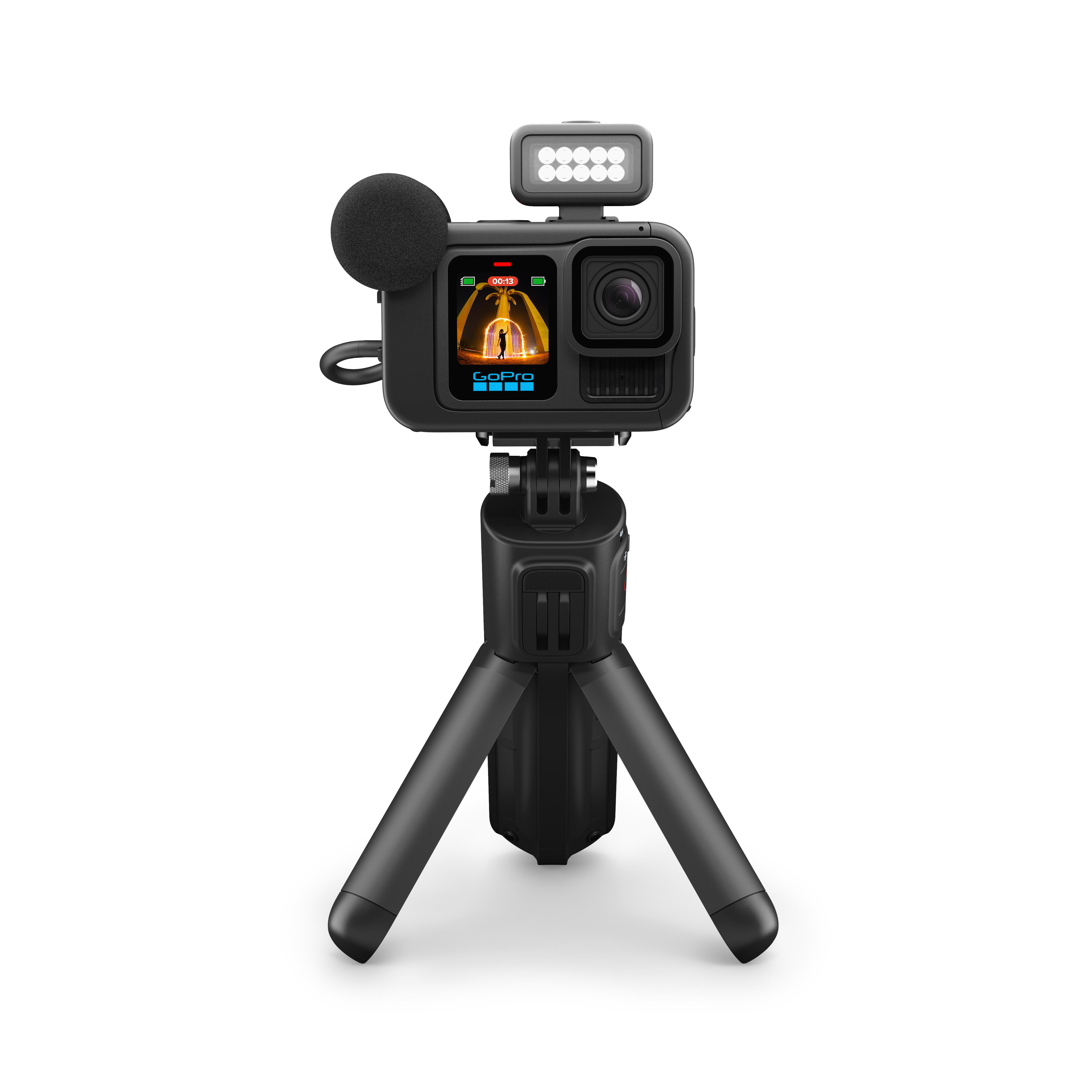 GoPro-Kamera mit Mikrofon, Licht und Stativ. Schwarz-Weiß, schräge Ansicht.