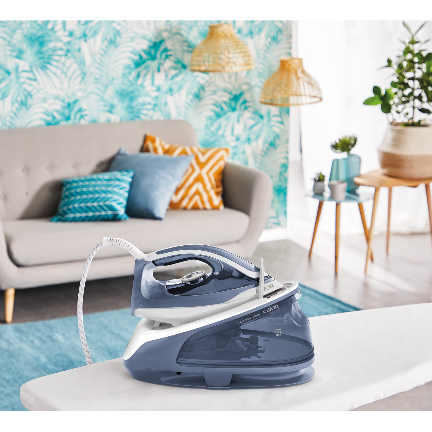A blue and white iron on an ironing board with a floral wallpaper background.