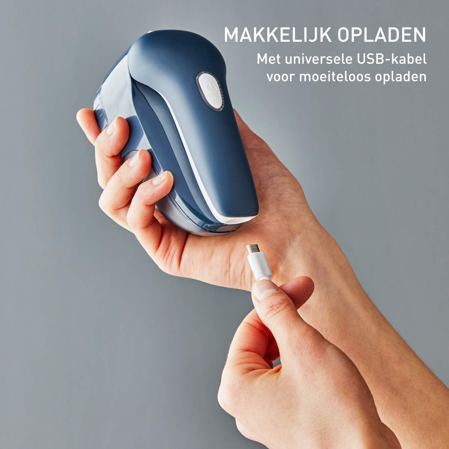 Handen houden een blauwe en witte pluizenverwijderaar vast met een USB-kabel, met tekst erboven in het Nederlands.