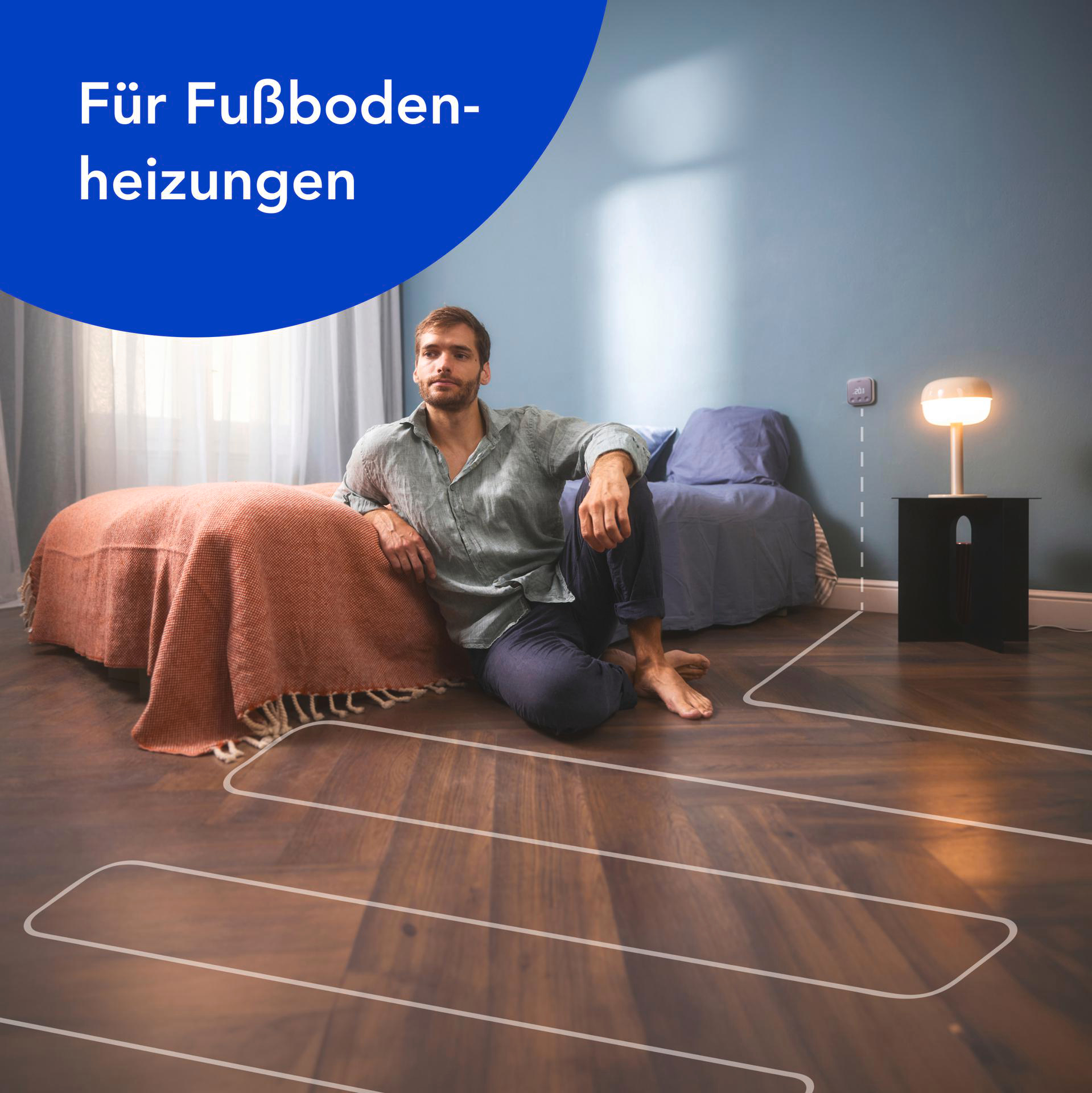 Frau und Mann in einem Raum, mit einem Thermostat an der Wand. Thermostat-Anzeige sichtbar.