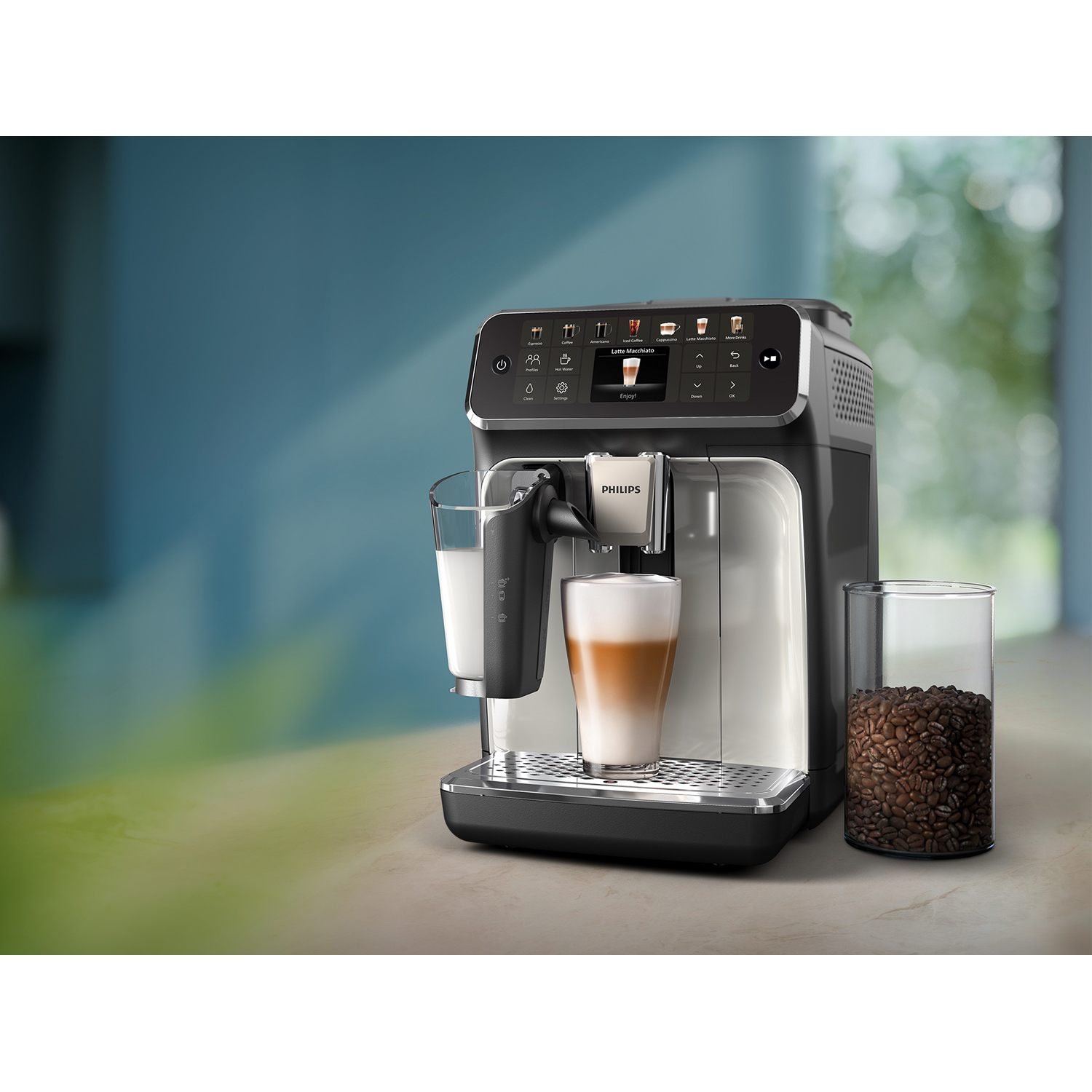 Una macchina per espresso Philips con un bicchiere di latte, un latte e un barattolo di chicchi di caffè su un bancone.