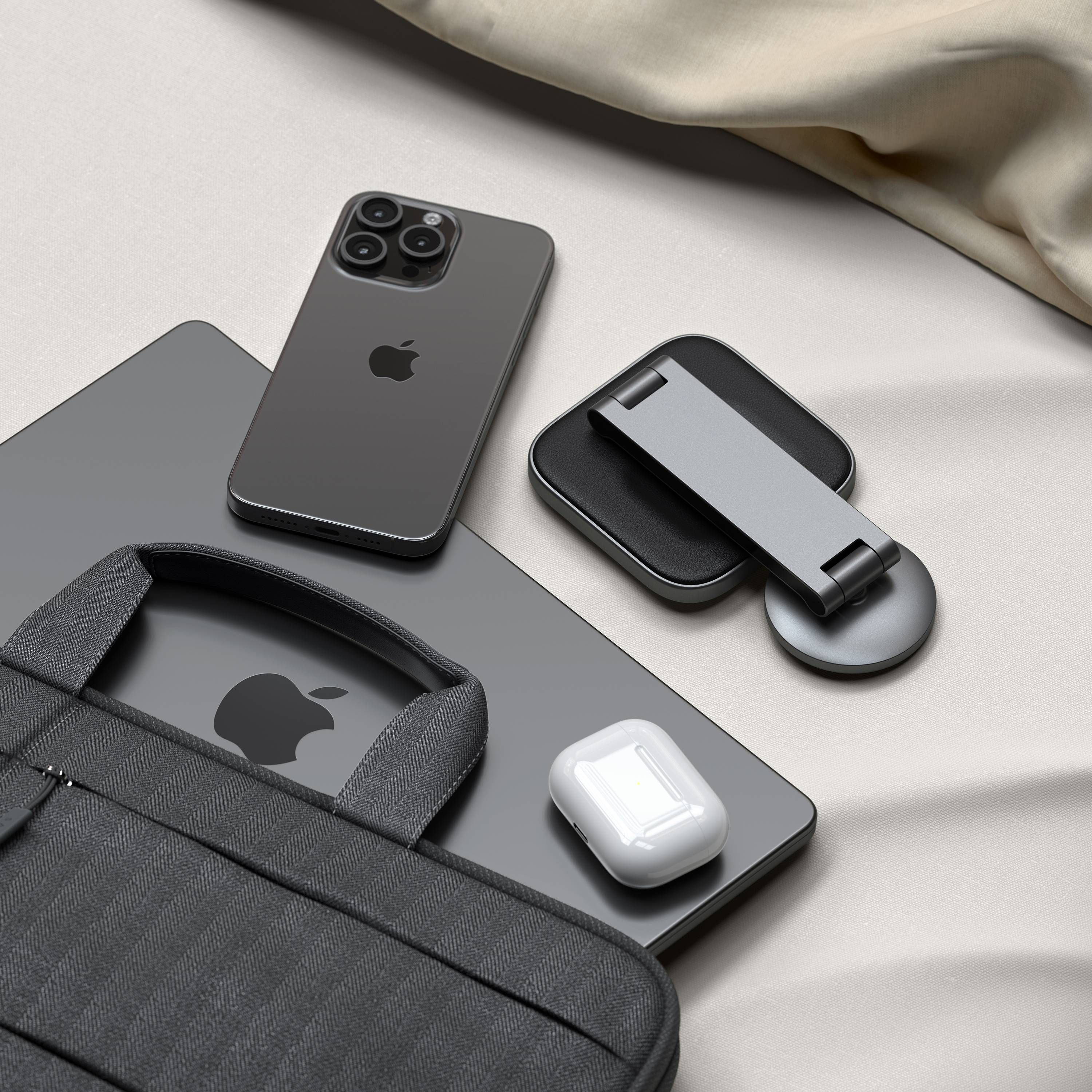 Un laptop, iPhone, AirPods e un supporto su una superficie chiara.