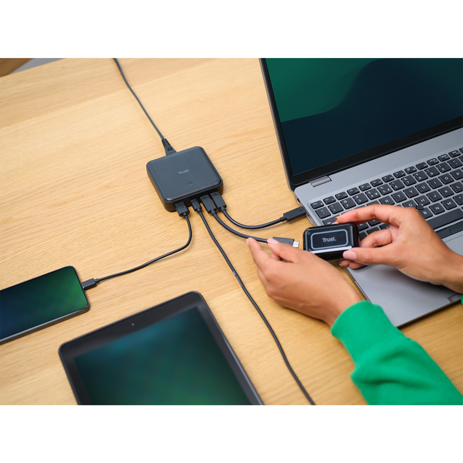 Un setup da scrivania con laptop, tablet e telefono collegati a un hub.