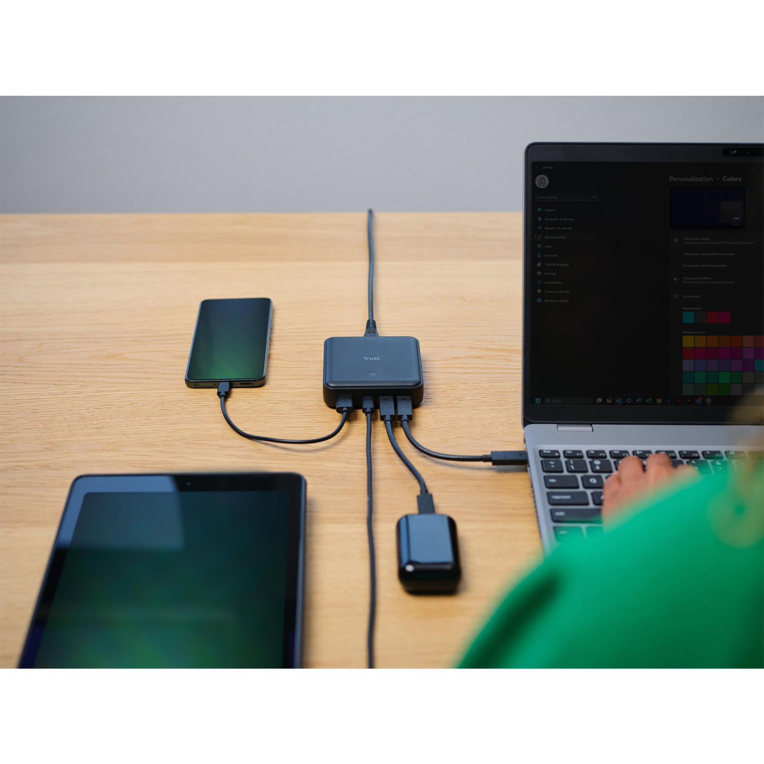 Un laptop, un telefono, un tablet e un hub di ricarica sono sulla scrivania.