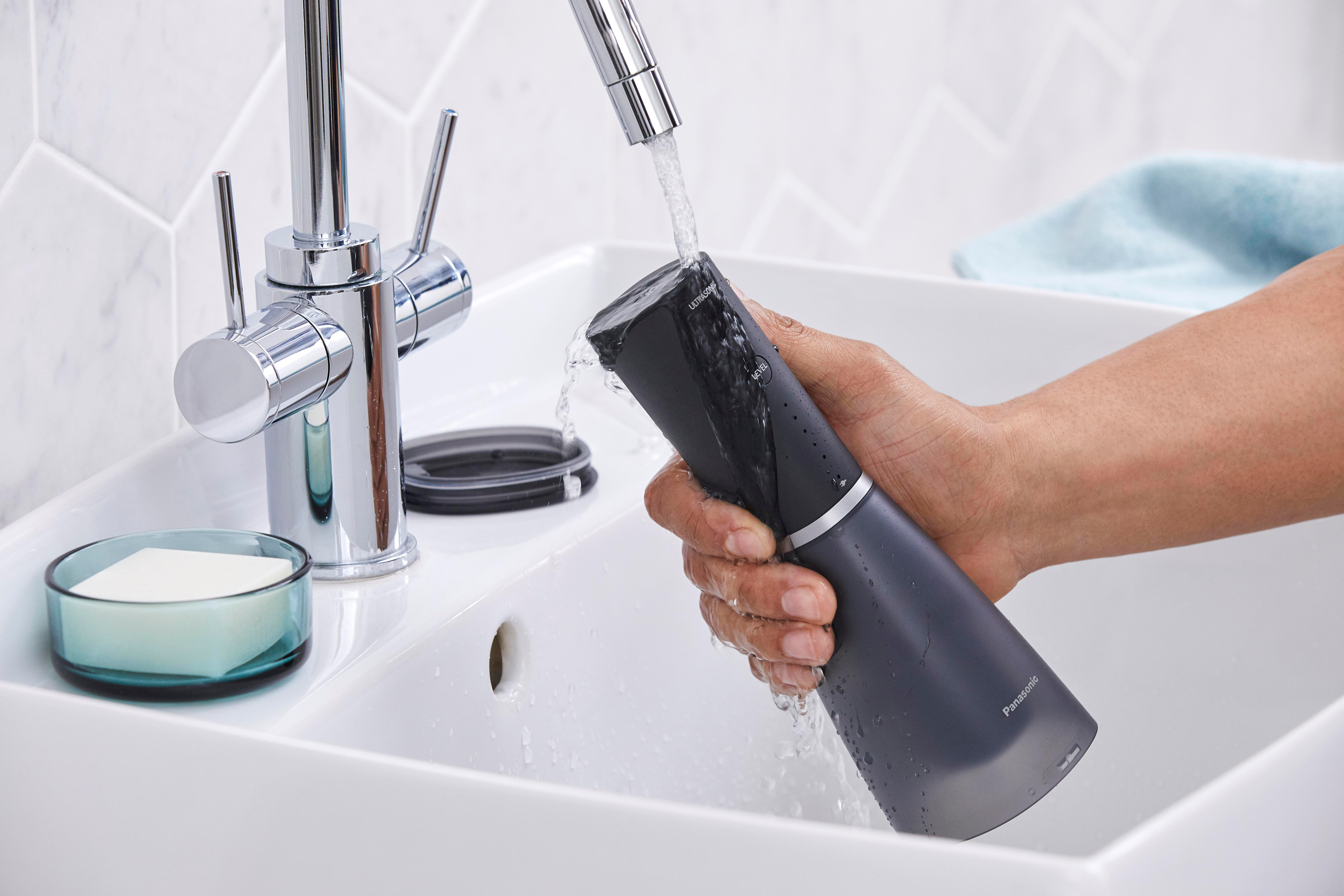 Ein schwarzer Wasserflosser wird in einem weißen Waschbecken von einer Hand gewaschen.