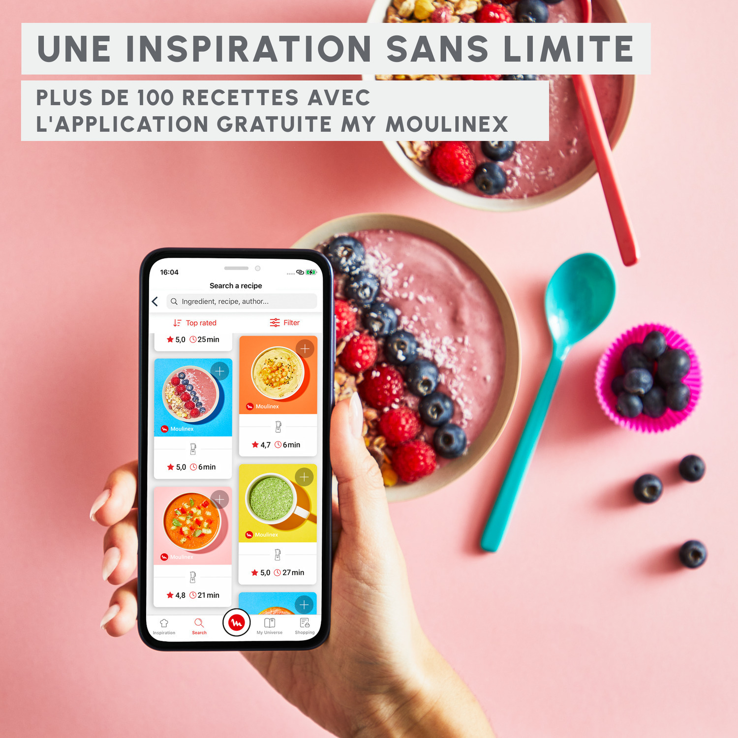 Une main tenant un téléphone affiche une application de cuisine avec des recettes sur fond rose.