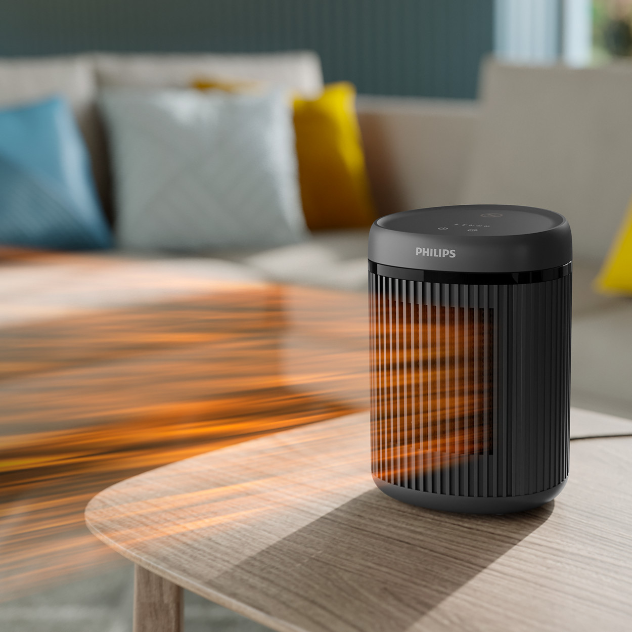 Schwarzer Philips-Heizlüfter auf Holztisch. Orange Wärmestrahlen. Couch und Kissen im Hintergrund.