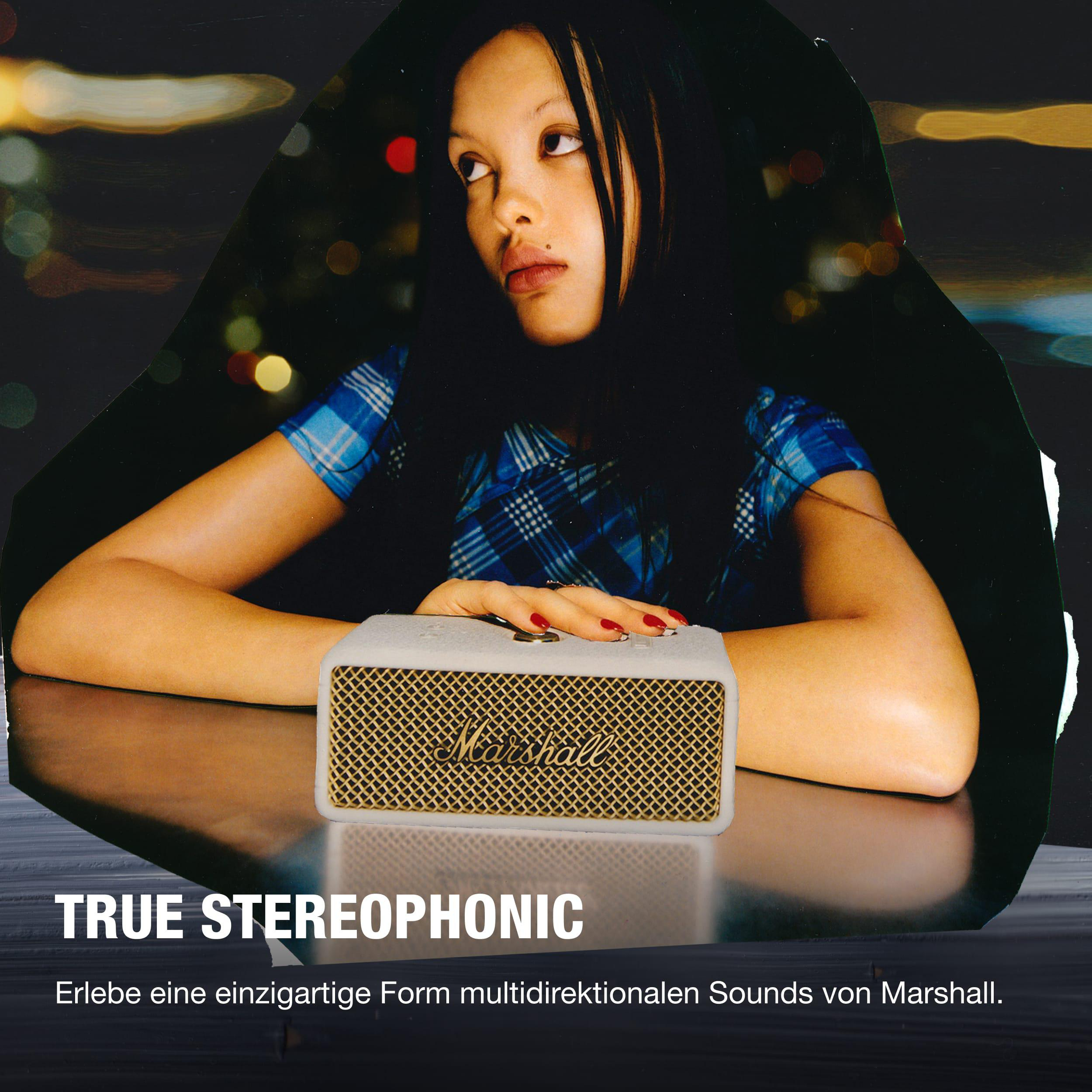 Frau blickt weg, in der Nähe eines Marshall Bluetooth-Lautsprechers auf dem Tisch.