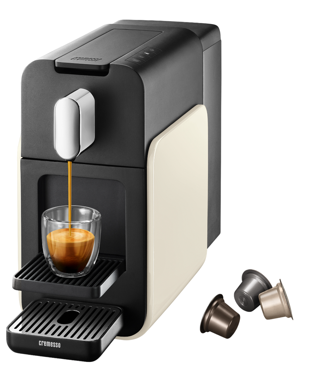 Schwarze und cremefarbene Espressomaschine, die Kaffee in ein klares Glas brüht. Drei Kaffeekapseln liegen daneben.