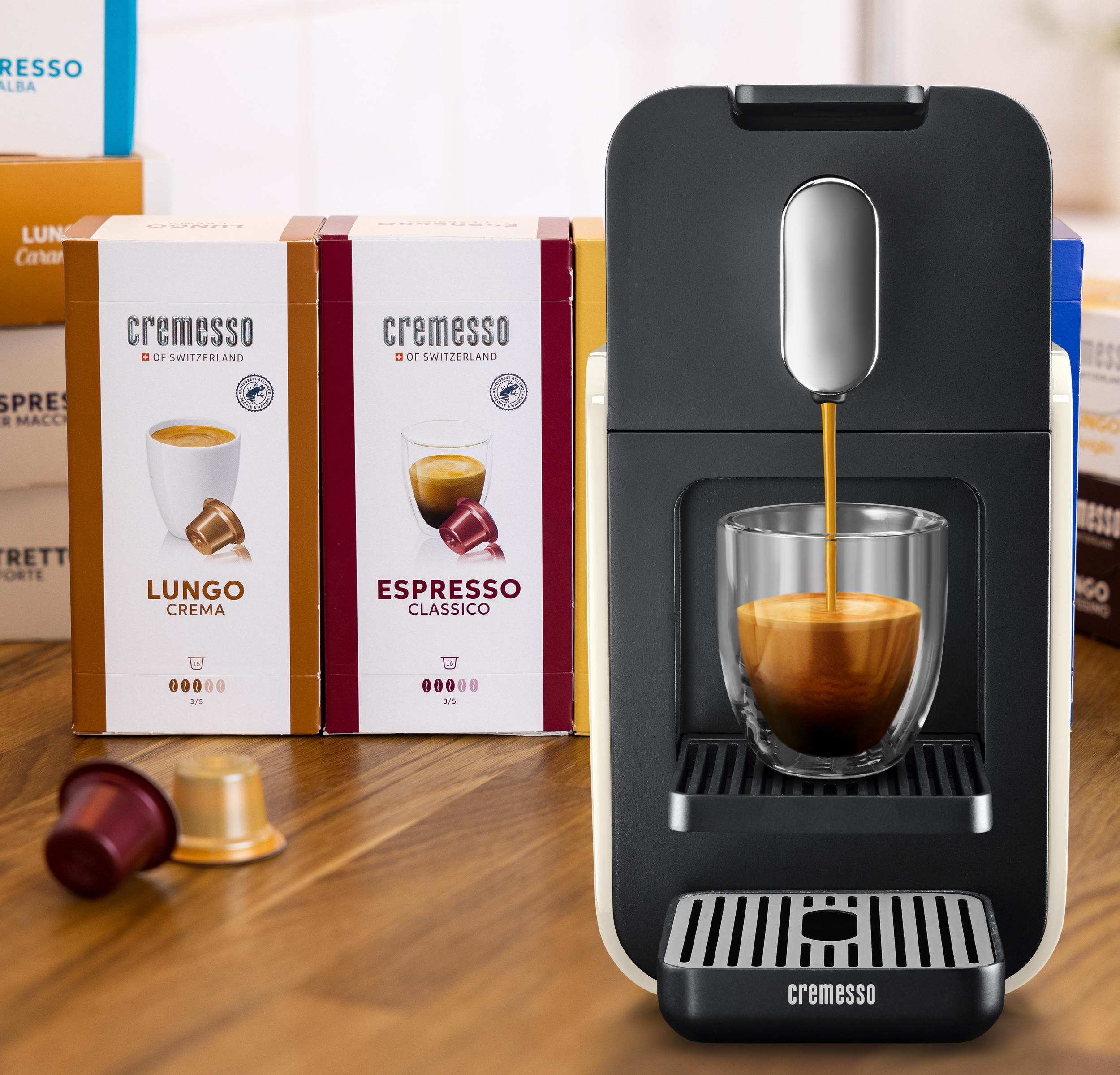 Kaffeemaschine, die Kaffee in eine Glastasse ausgibt. Kaffeepads links.