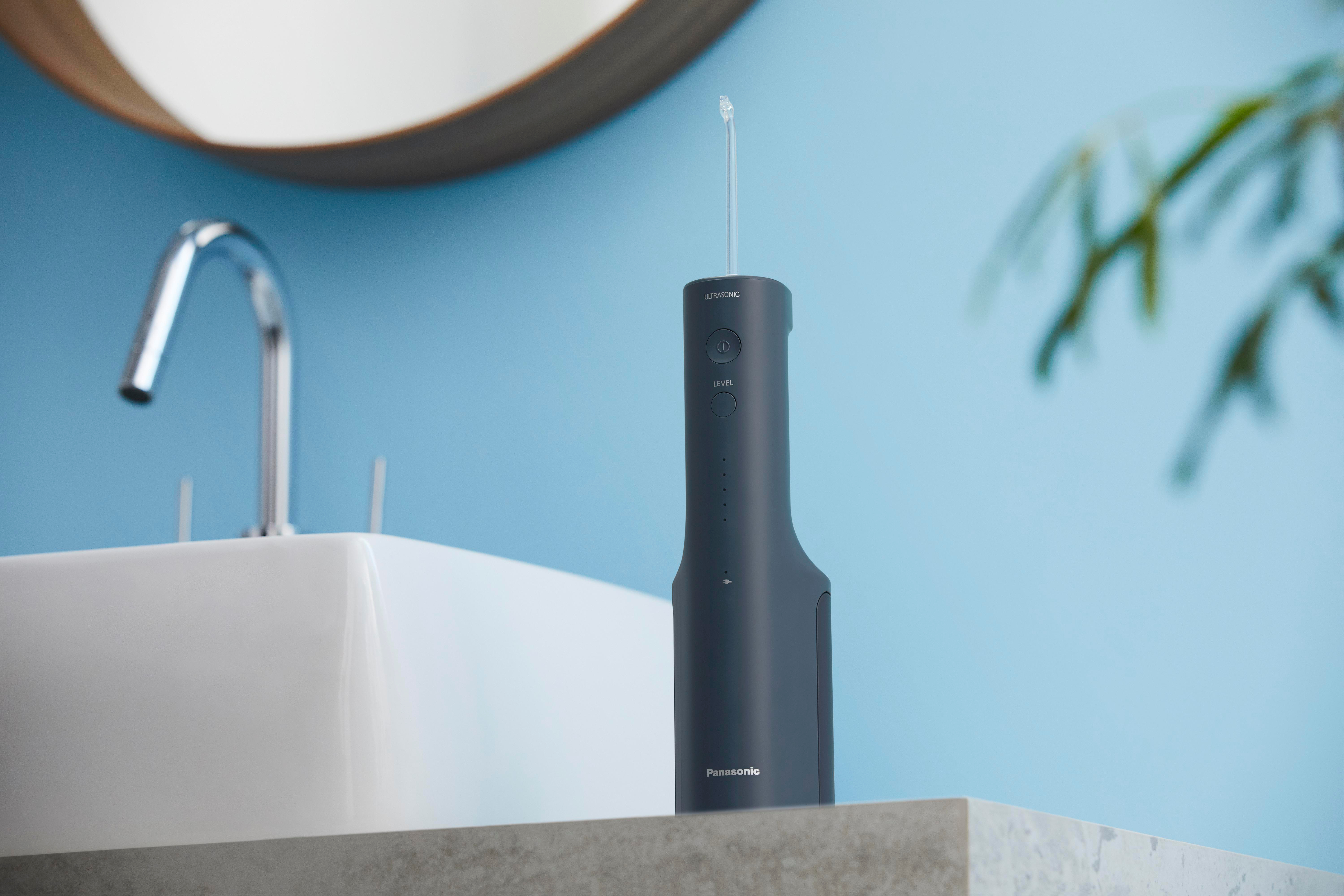 Ein grauer Wasserflosser auf einer Arbeitsplatte in der Nähe eines Waschbeckens und eines Spiegels.