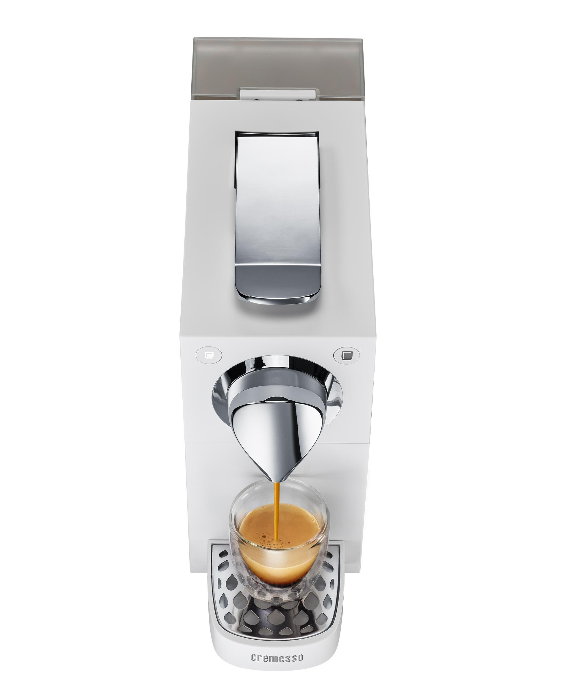 Weiße Kaffeemaschine, die Espresso in ein Glas abgibt, mit einem Chromauslauf.