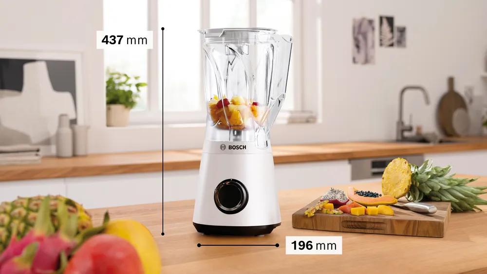 Fehér turmixgép gyümölccsel, fa pulton. Gyümölcsök: ananász, papaya és sárkánygyümölcs.