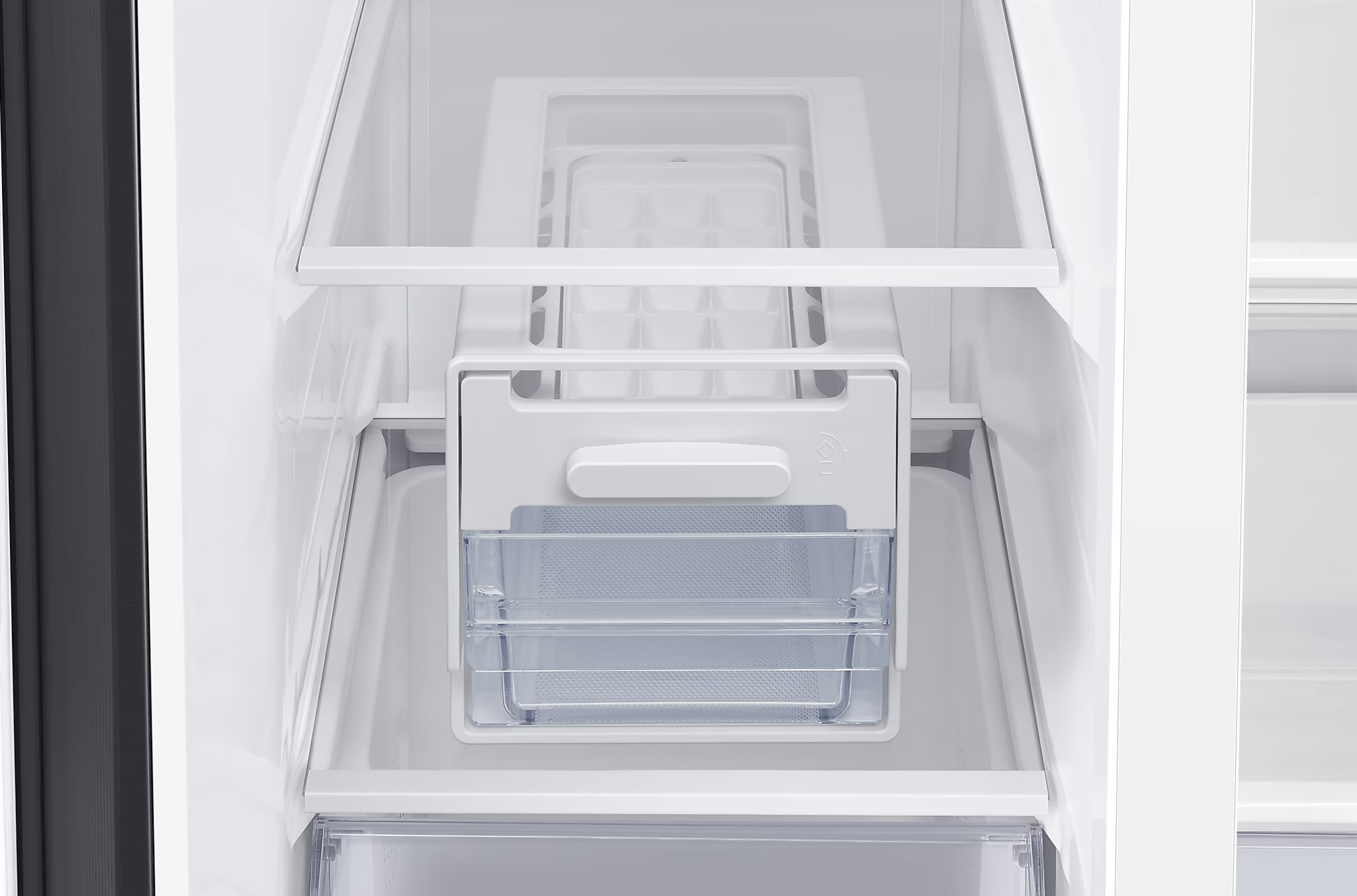 Wewnątrz lodówki widoczna jest kostkarka. Taca i schowek na lód są z przezroczystego plastiku.
