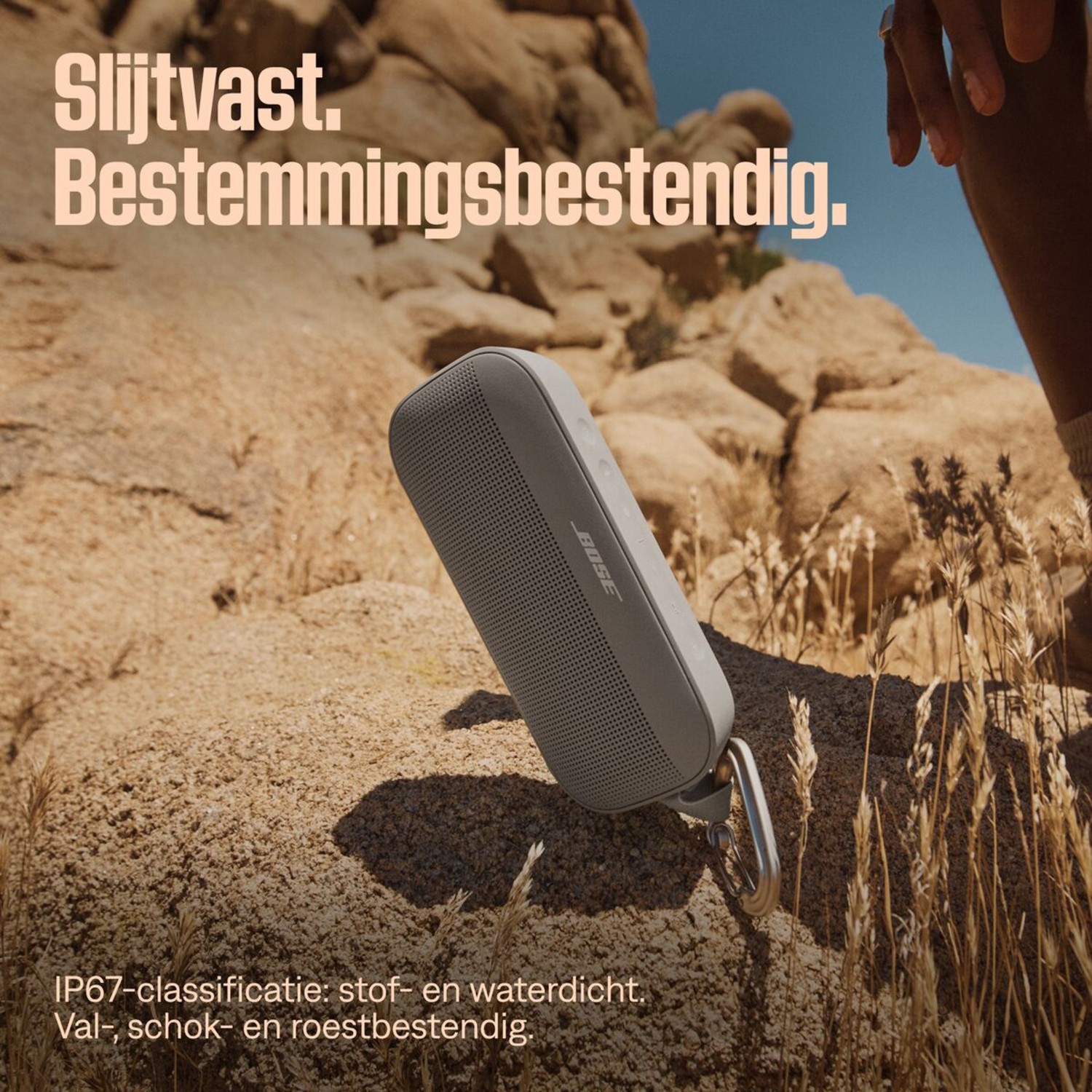 Grey Bose speaker on a rock, with text in Dutch.