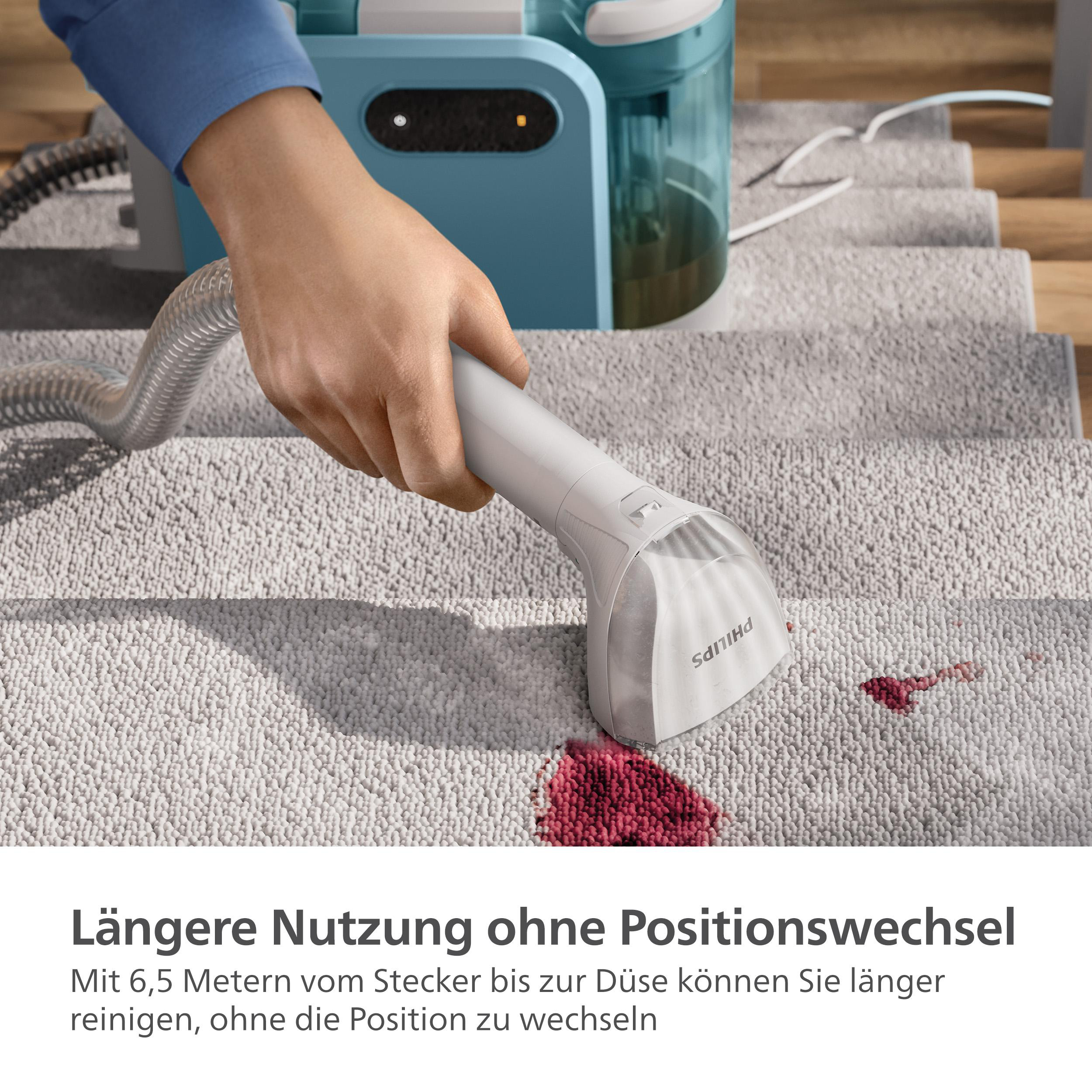 Eine Person reinigt einen hellgrauen Teppich mit einem Philips Dampfreiniger und entfernt einen roten Fleck.