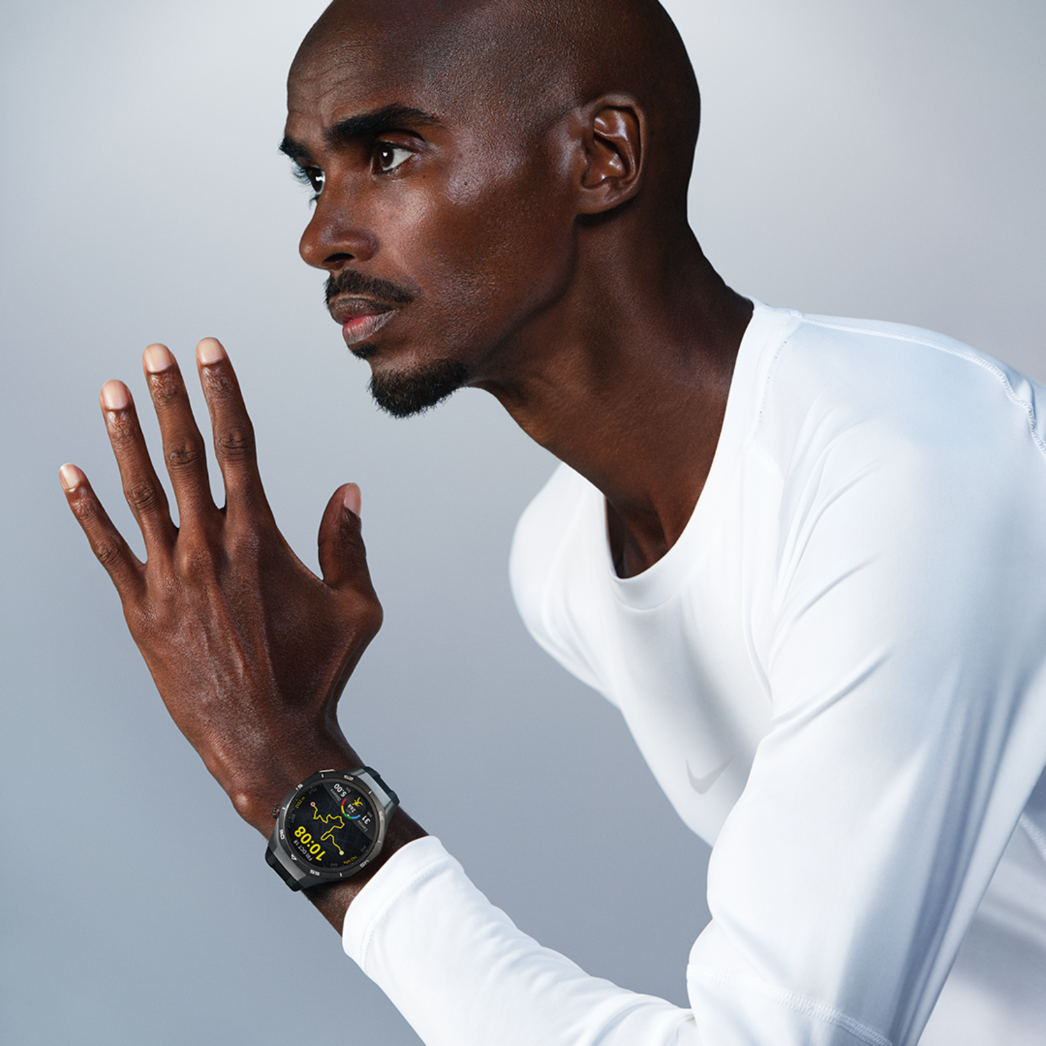 Een hardloper met een zwarte smartwatch, rennend met een vastberaden uitdrukking op een grijze achtergrond.