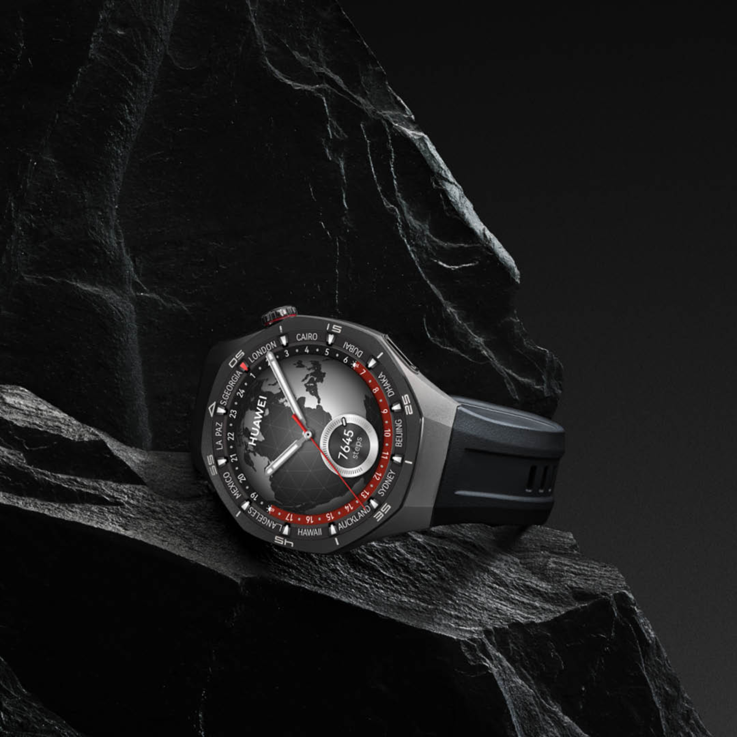Een zwart-grijze smartwatch met een wereldkaartdisplay die rust op een donker, getextureerd rots oppervlak.
