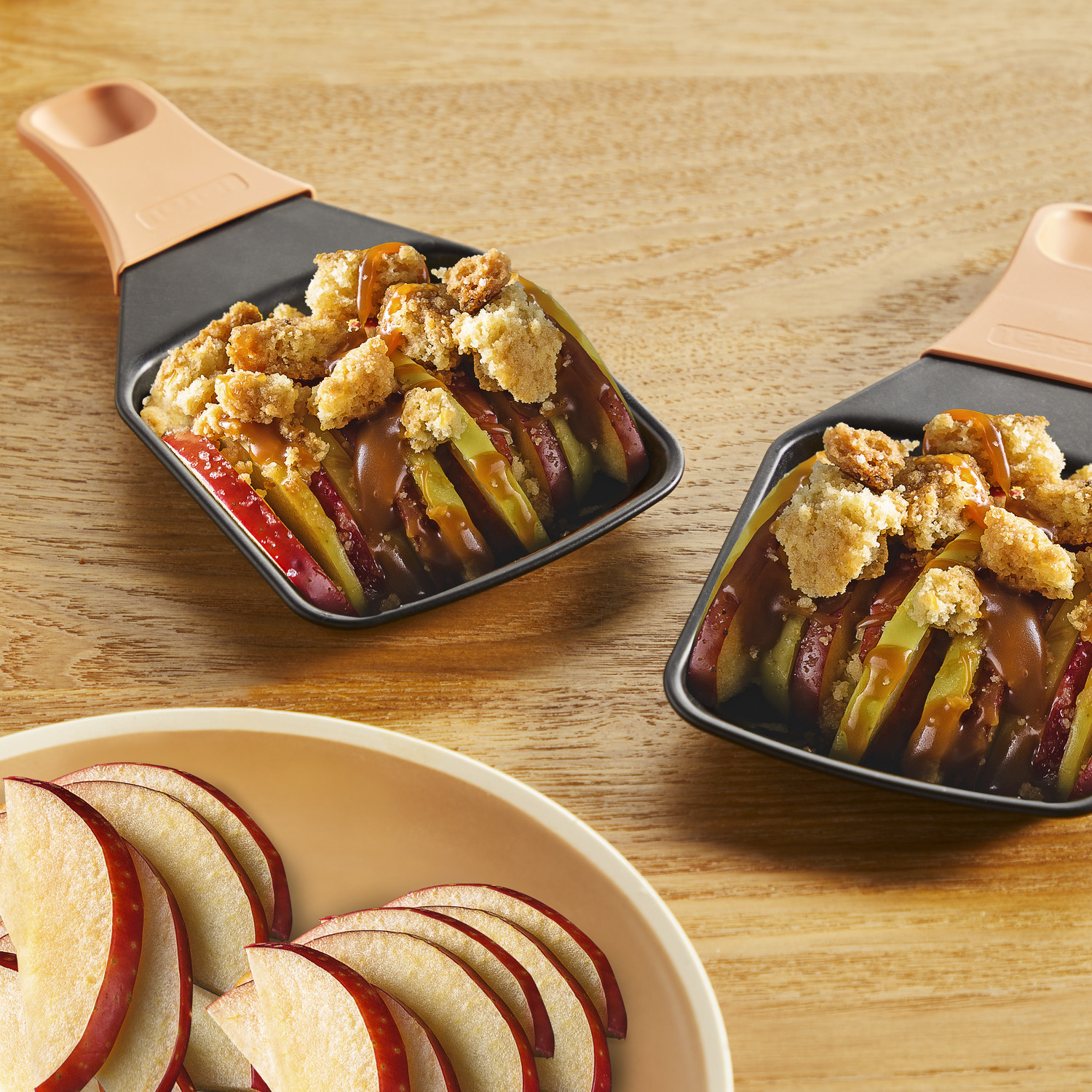 Two apple crumbles in small pans, and sliced apples.