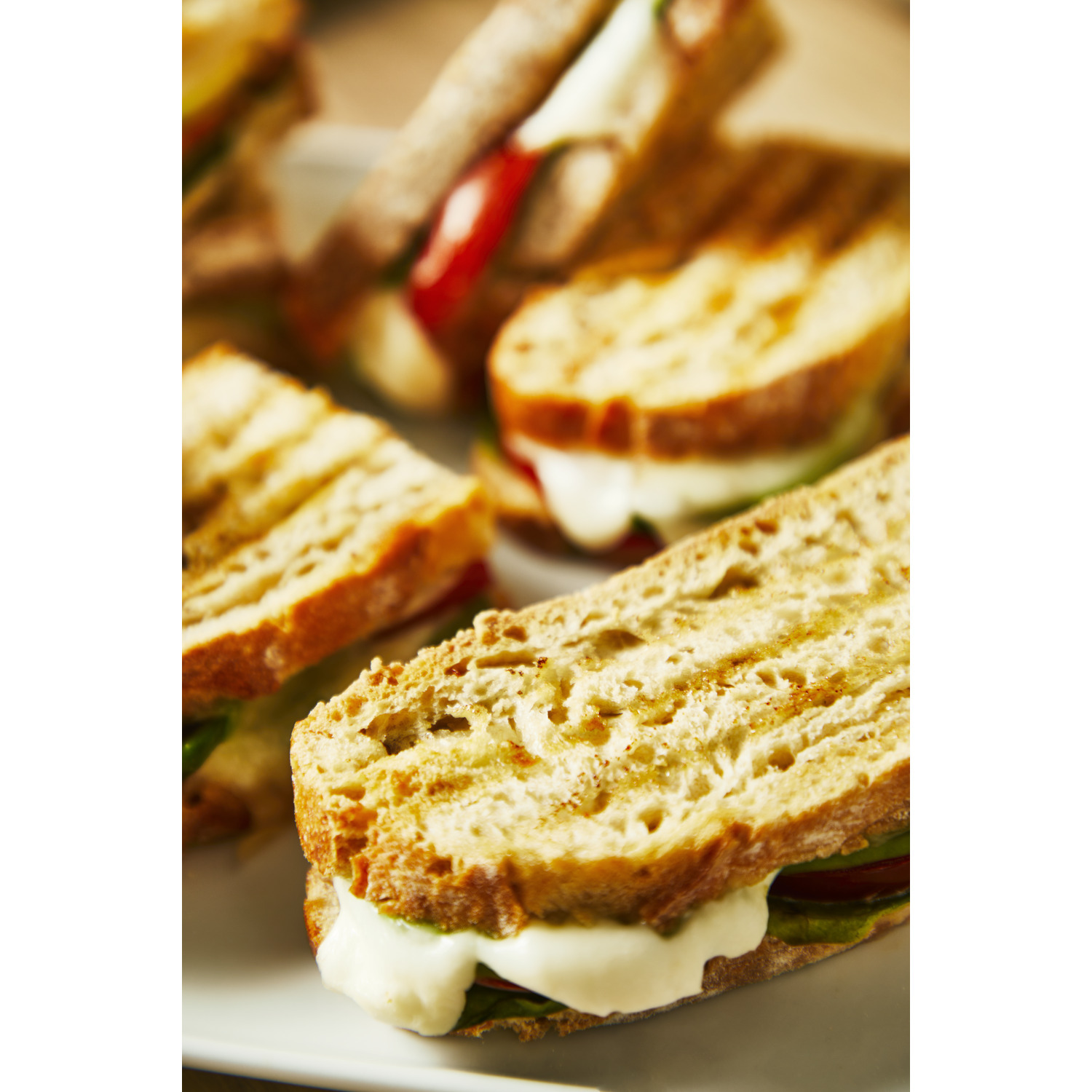 Close-up of grilled sandwiches with melted cheese and fillings. The bread is golden brown.