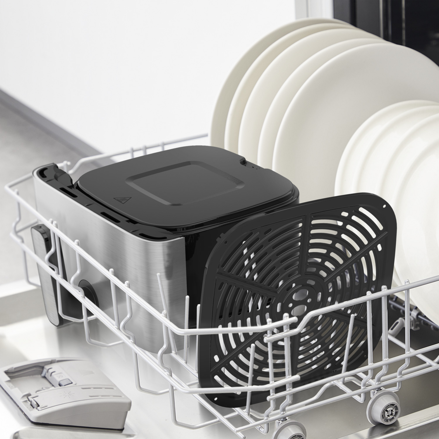 An air fryer with a black basket inside a dishwasher with white dishes.