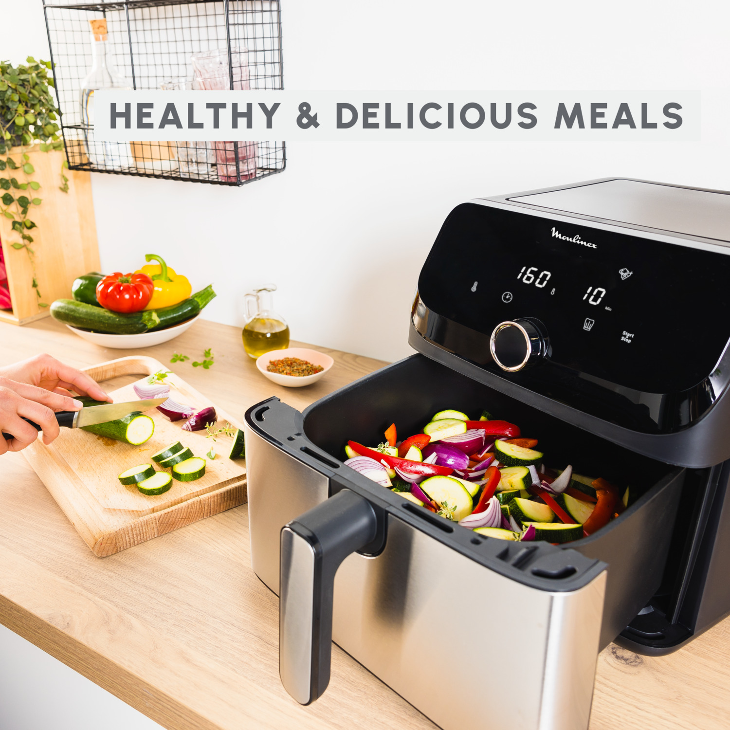 An air fryer with vegetables inside, a person slicing vegetables and a text "HEALTHY & DELICIOUS MEALS".